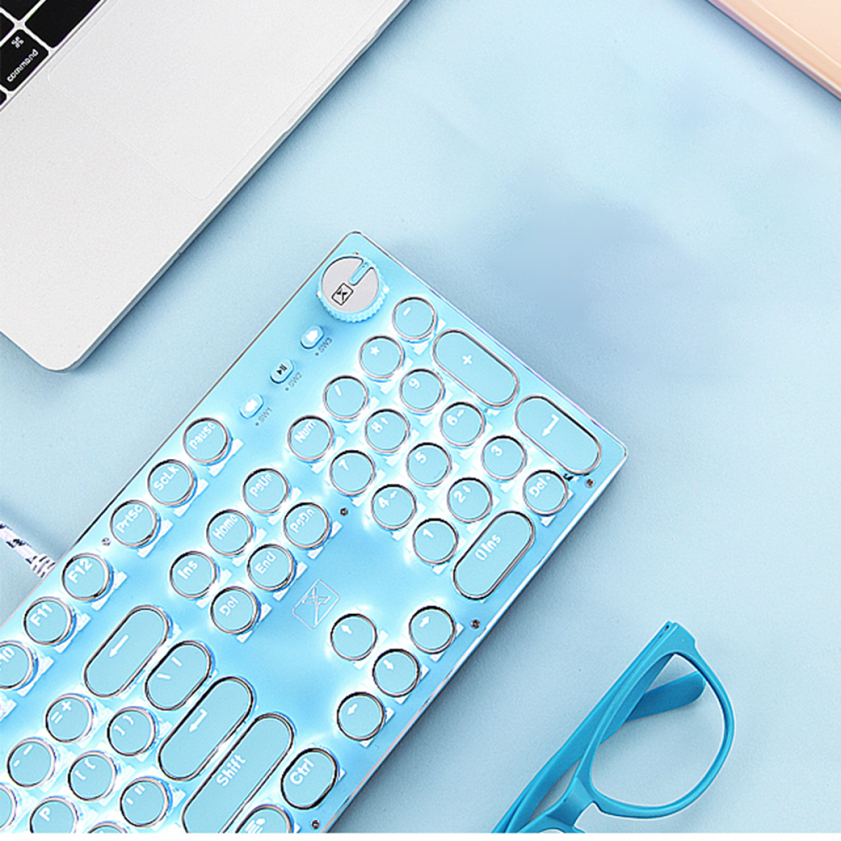 Nahaufnahme einer blauen Tastatur mit runden Tasten. Eine blaue Brille liegt auf dem Tisch.