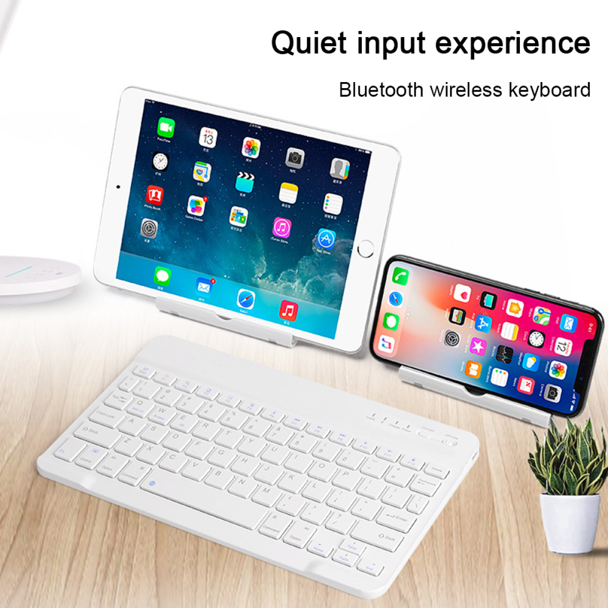 Kabellose Tastatur, iPad und Smartphone auf Ständern. Pflanze auf Holztisch. Text oben.