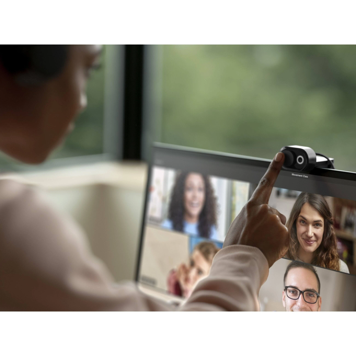 Osoba wskazująca na ekran laptopa z rozmową wideo.