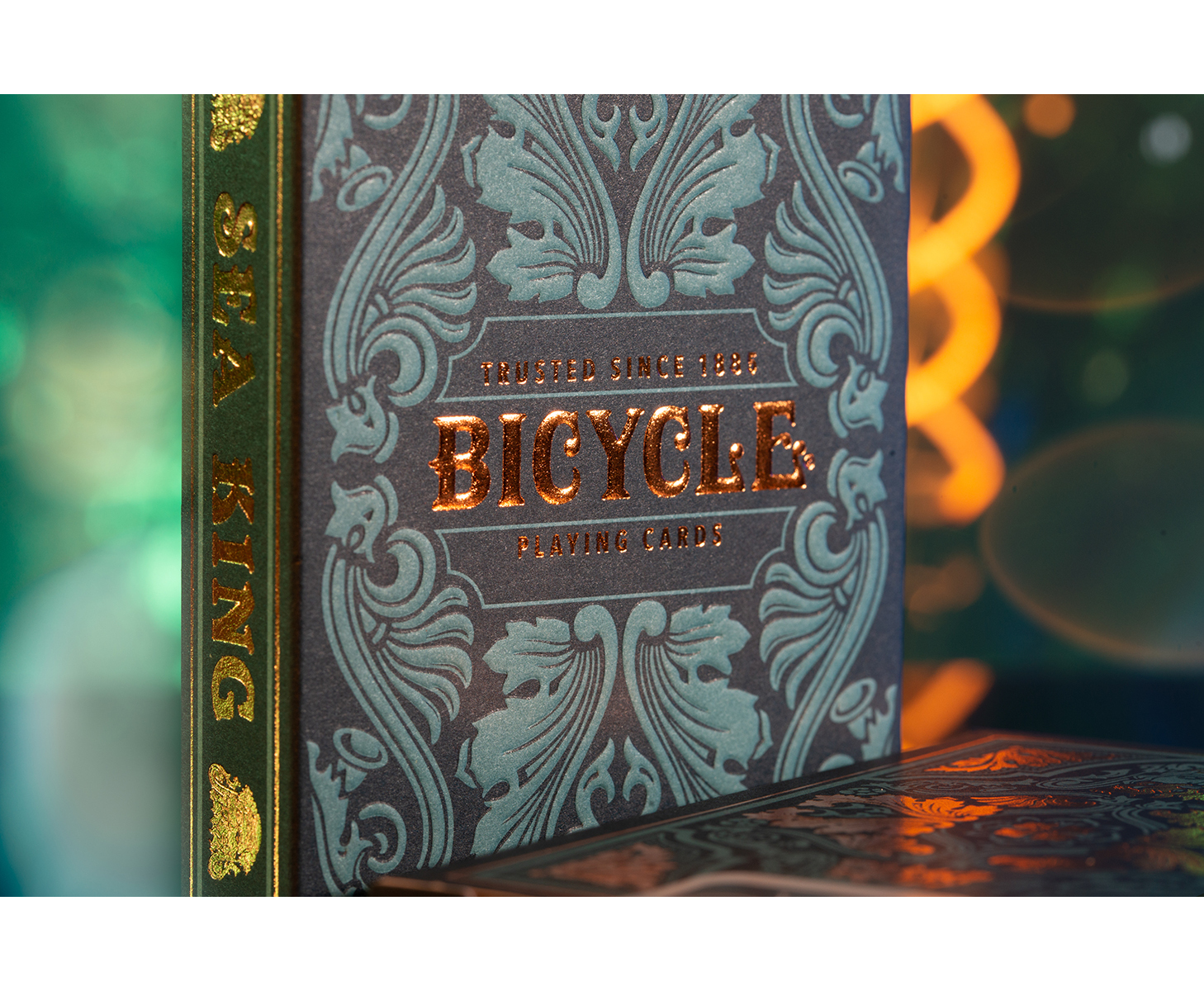 Nahaufnahme einer Bicycle-Spielkartenbox. Die Box ist dunkel mit teal und goldenen Akzenten, der Text ist goldfarben.
