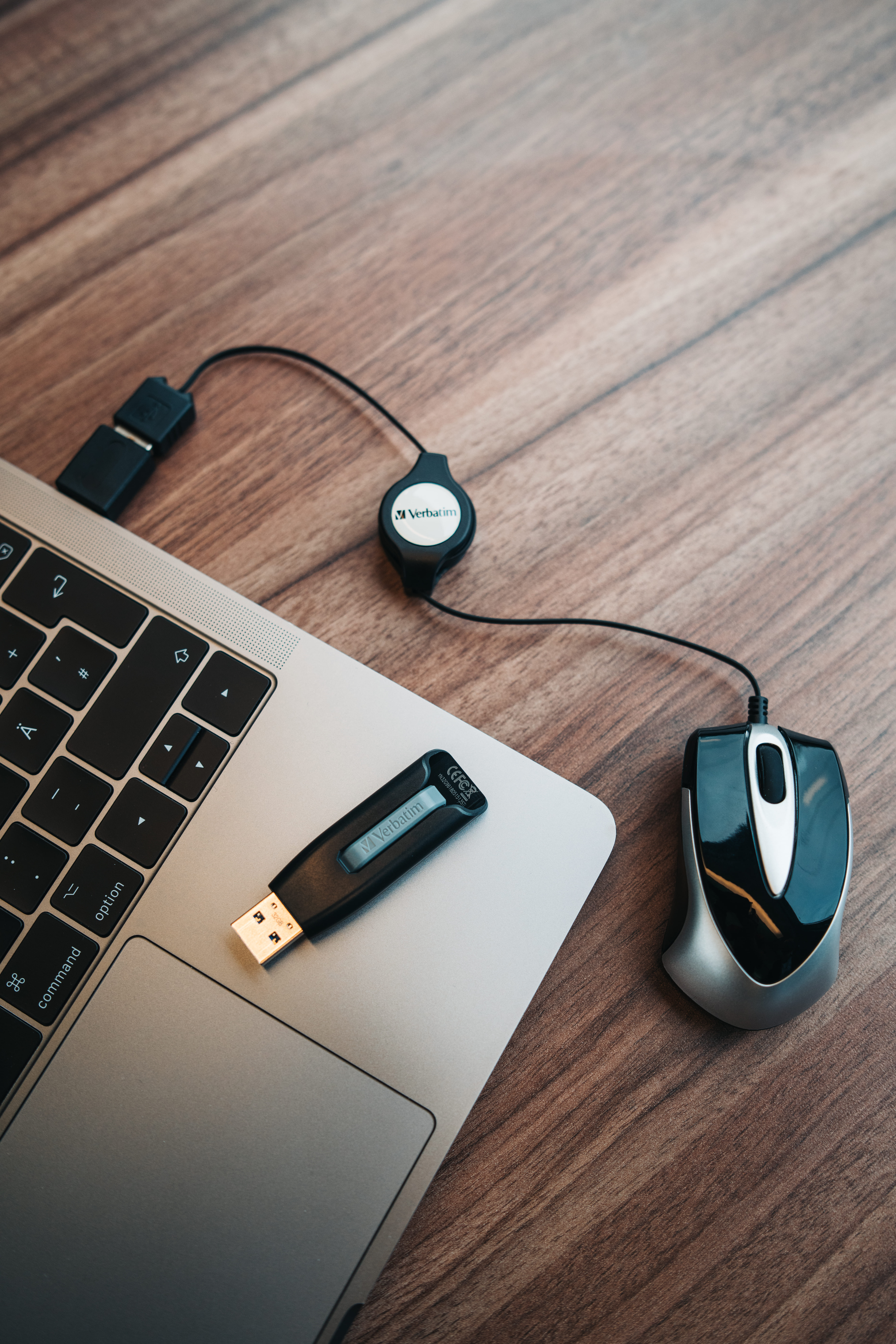 Laptop mit angeschlossener USB-Festplatte und Maus auf einer Holzoberfläche.