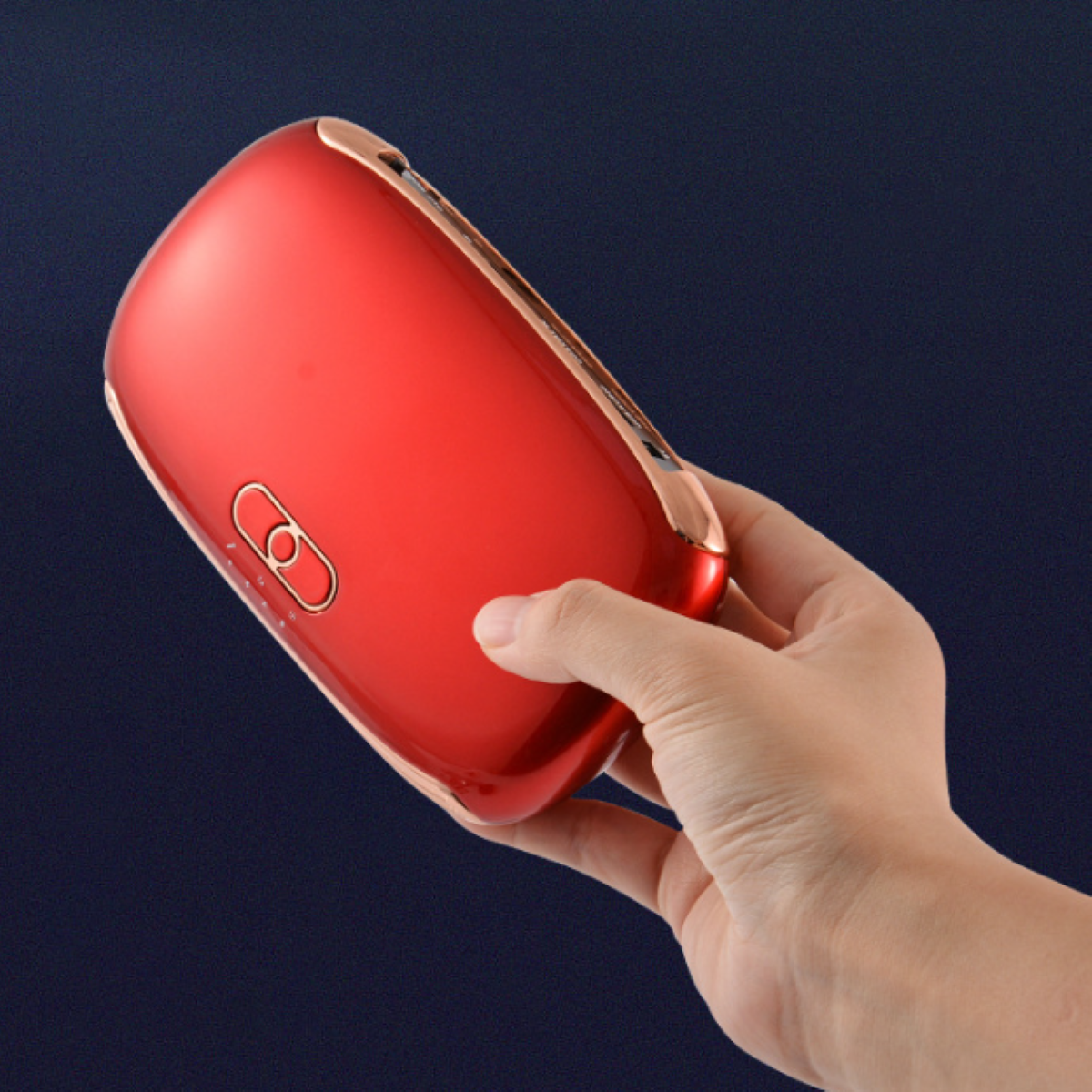 Ein rotes Handgerät mit roségoldfarbener Umrandung, gehalten von einer Hand vor blauem Hintergrund.