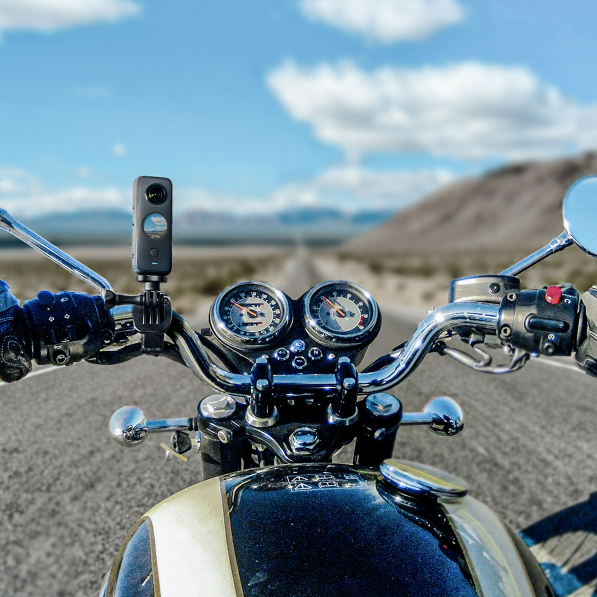 Motorradlenker mit montierter Action-Kamera, die auf einer Straße mit malerischem Hintergrund fährt.