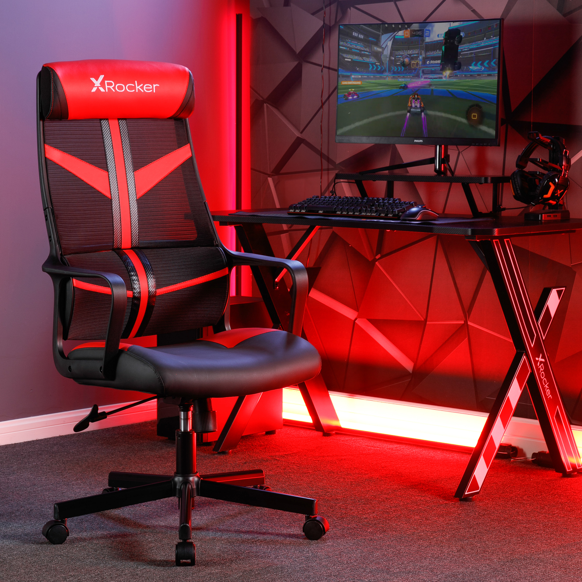 Roter und schwarzer Gaming-Stuhl mit Gaming-Setup in einem Raum.