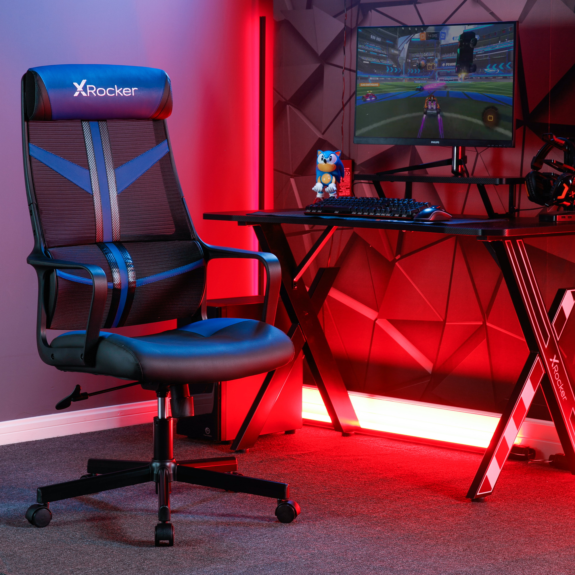Gaming-Stuhl mit blauem und schwarzem Design. Schreibtisch mit Monitor und Sonic-Figur.