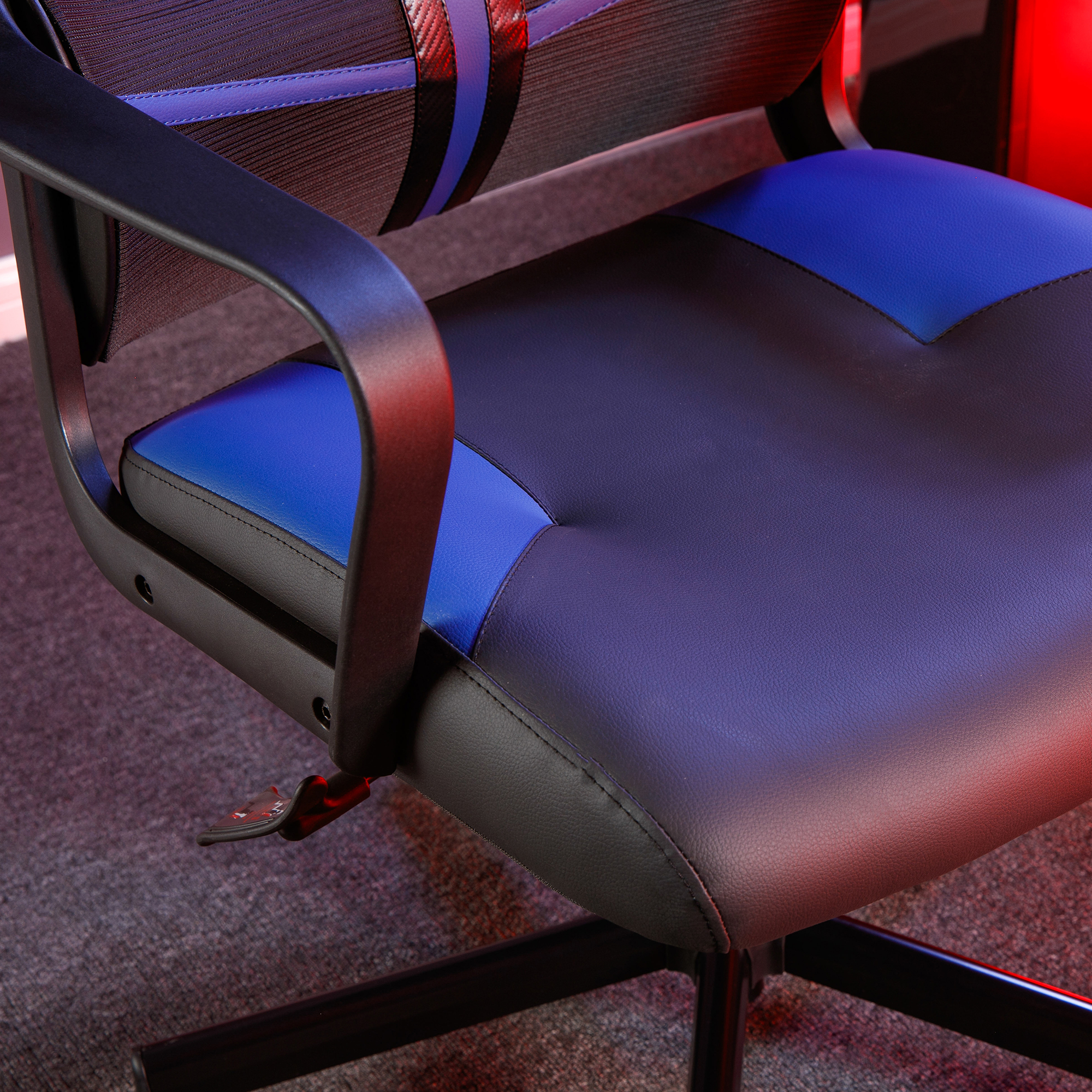 Gaming-Stuhl Detail: blauer und schwarzer Sitz mit Armlehnen und roten Akzenten.