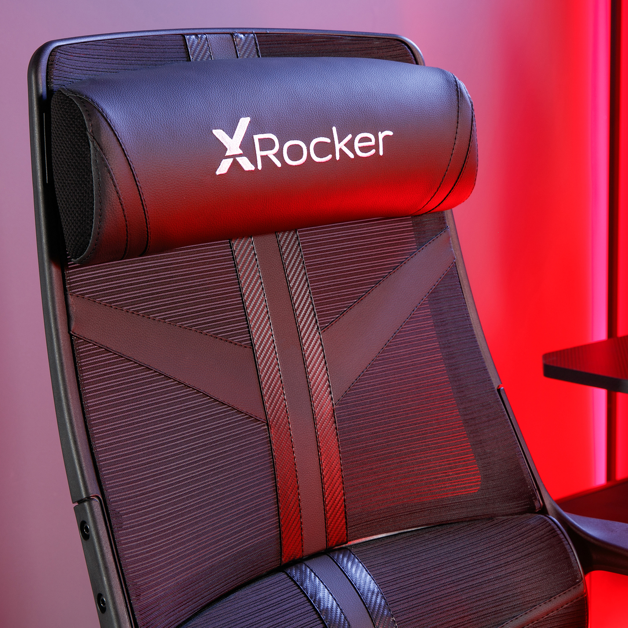 Schwarzer Gaming-Stuhl mit XRockers-Logo, Netzrücken, Kopfstütze. Roter Licht Hintergrund. Nahaufnahme.