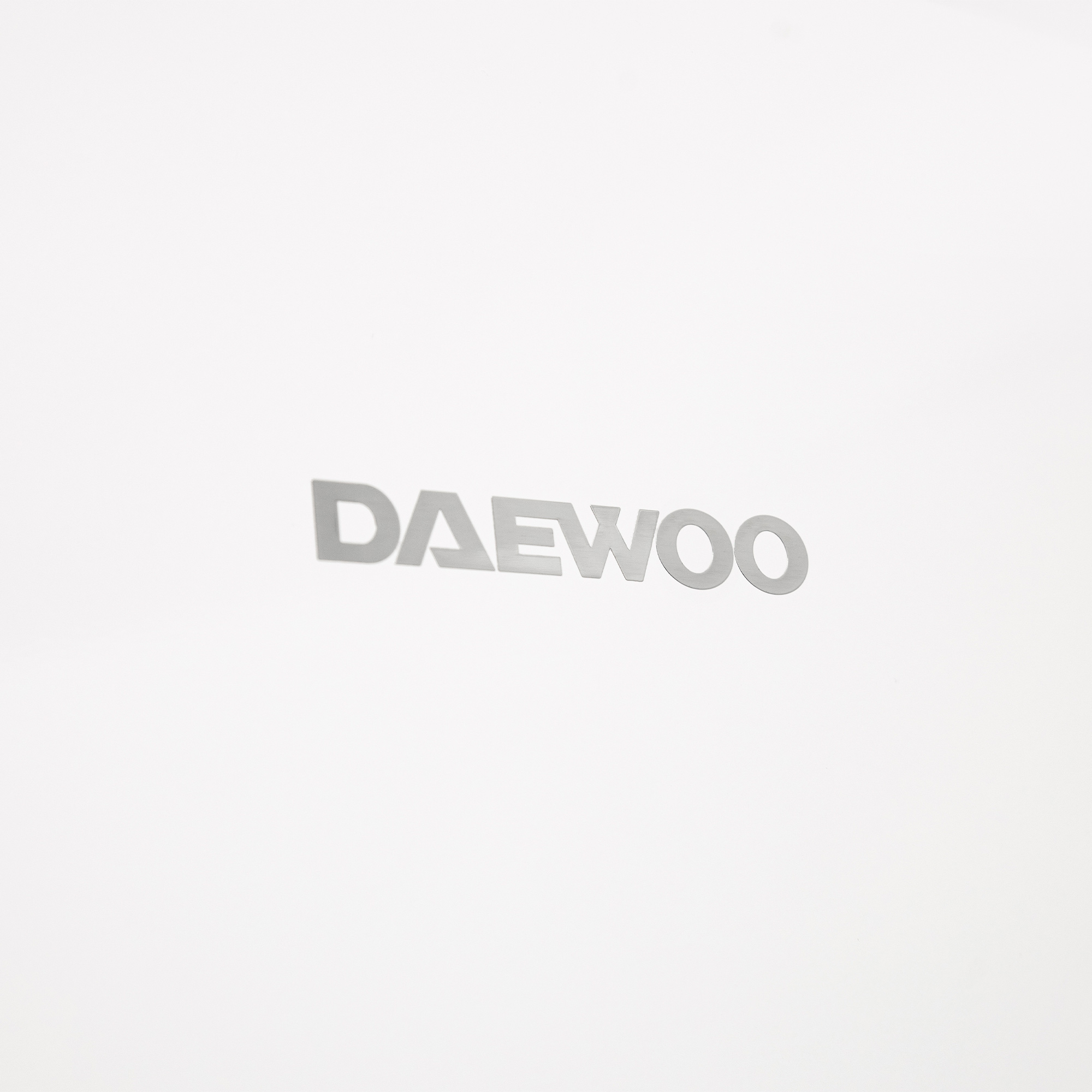 Das silberne 'DAEWOO'-Logo ist mittig auf einem schlichten weißen Hintergrund platziert.