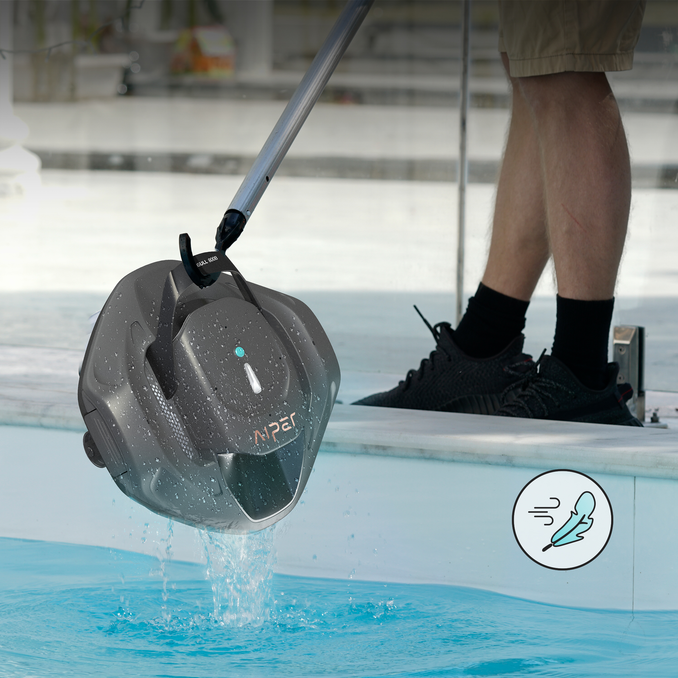 Una persona usa un pulitore per piscina con un lungo manico in una piscina. Spruzzi d'acqua.