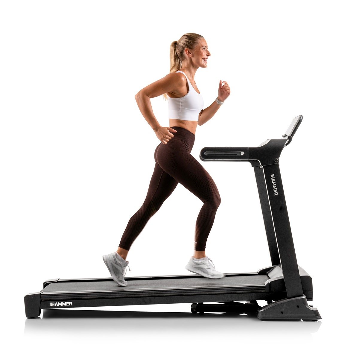 Frau läuft auf einem Laufband. Sie trägt Sportbekleidung. Das Laufband ist schwarz und hat eine digitale Anzeige.