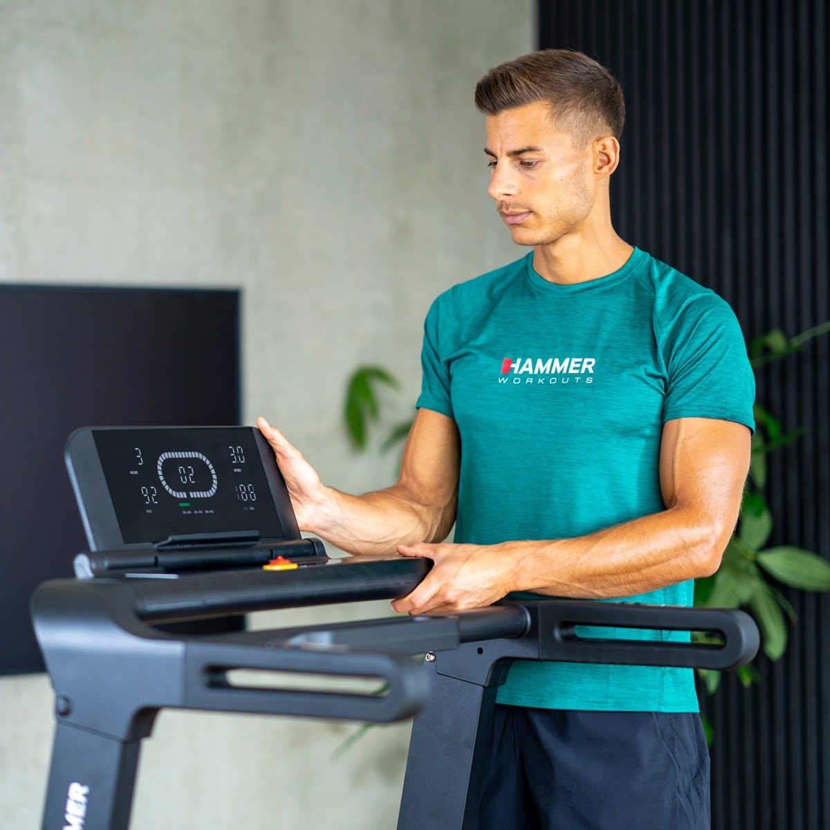 Mann auf Laufband, grünes Hemd, schwarze Shorts. Bildschirm zeigt Geschwindigkeit/Zeit. Home Gym, modernes Design.