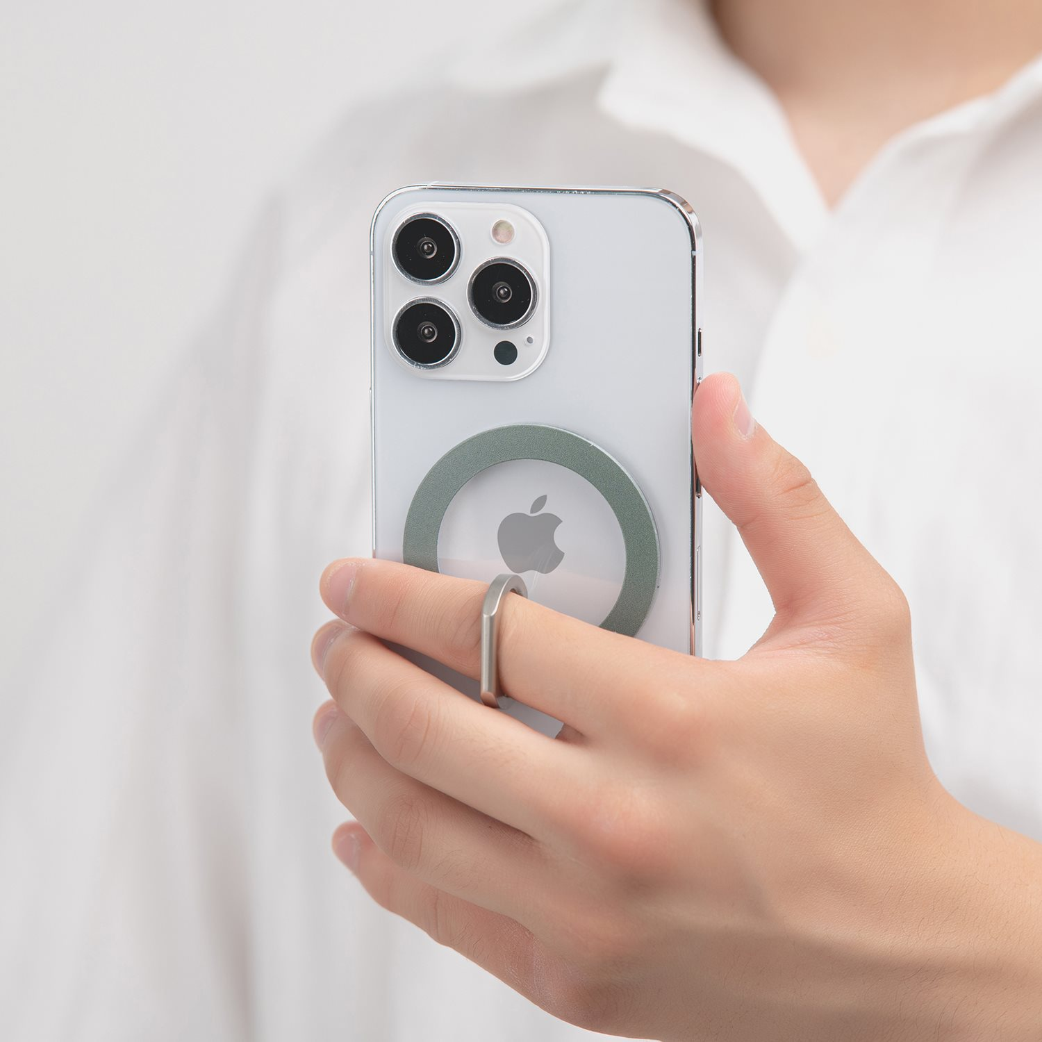 Eine Person hält ein helles Telefon mit einem Ringhalter. Der Hintergrund ist unscharf.