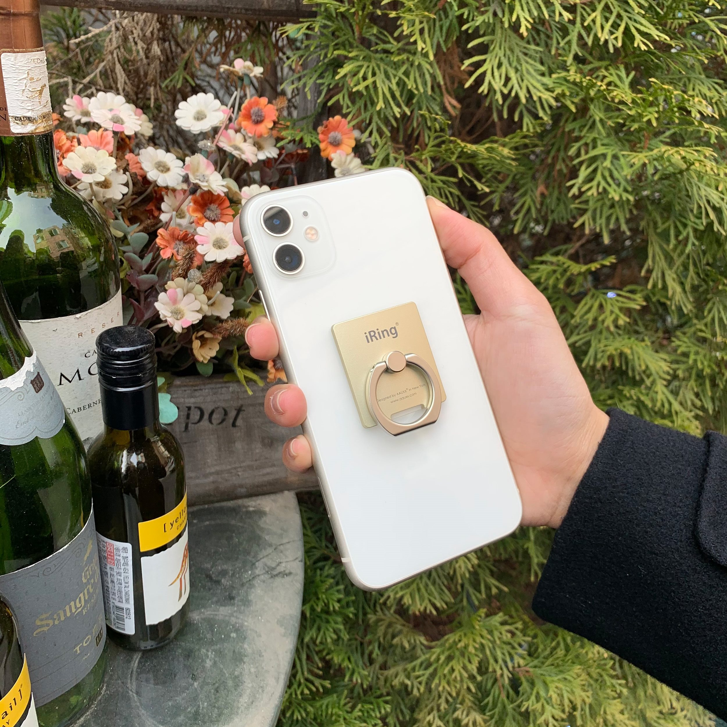 Eine Hand hält ein weißes Telefon mit einem Ringhalter.