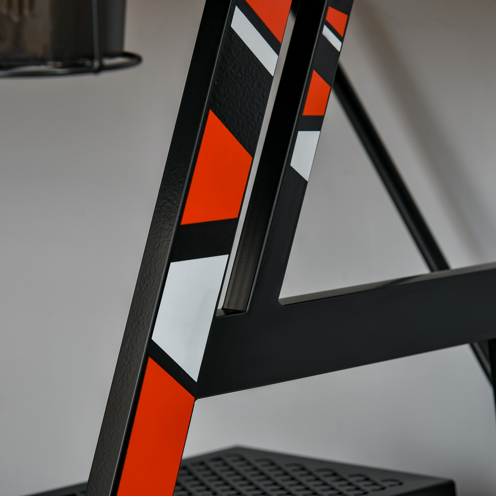 Escalera negra y metálica con diseño geométrico naranja, blanco y negro en el lateral.