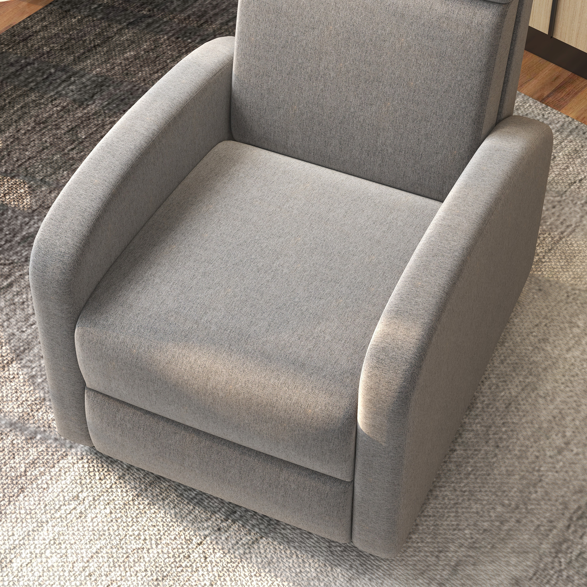 Un sillón gris en una toma cenital. La silla está sobre una alfombra estampada. La escena está bien iluminada.