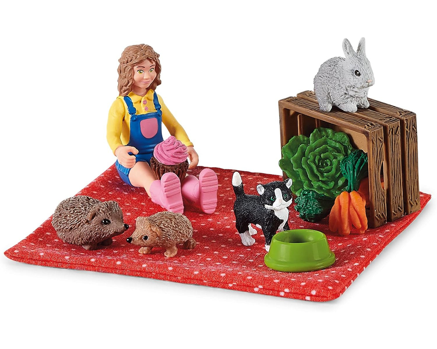 Ein Mädchen mit einem Cupcake, Igeln, einer Katze und einem Kaninchen auf einer roten Matte.