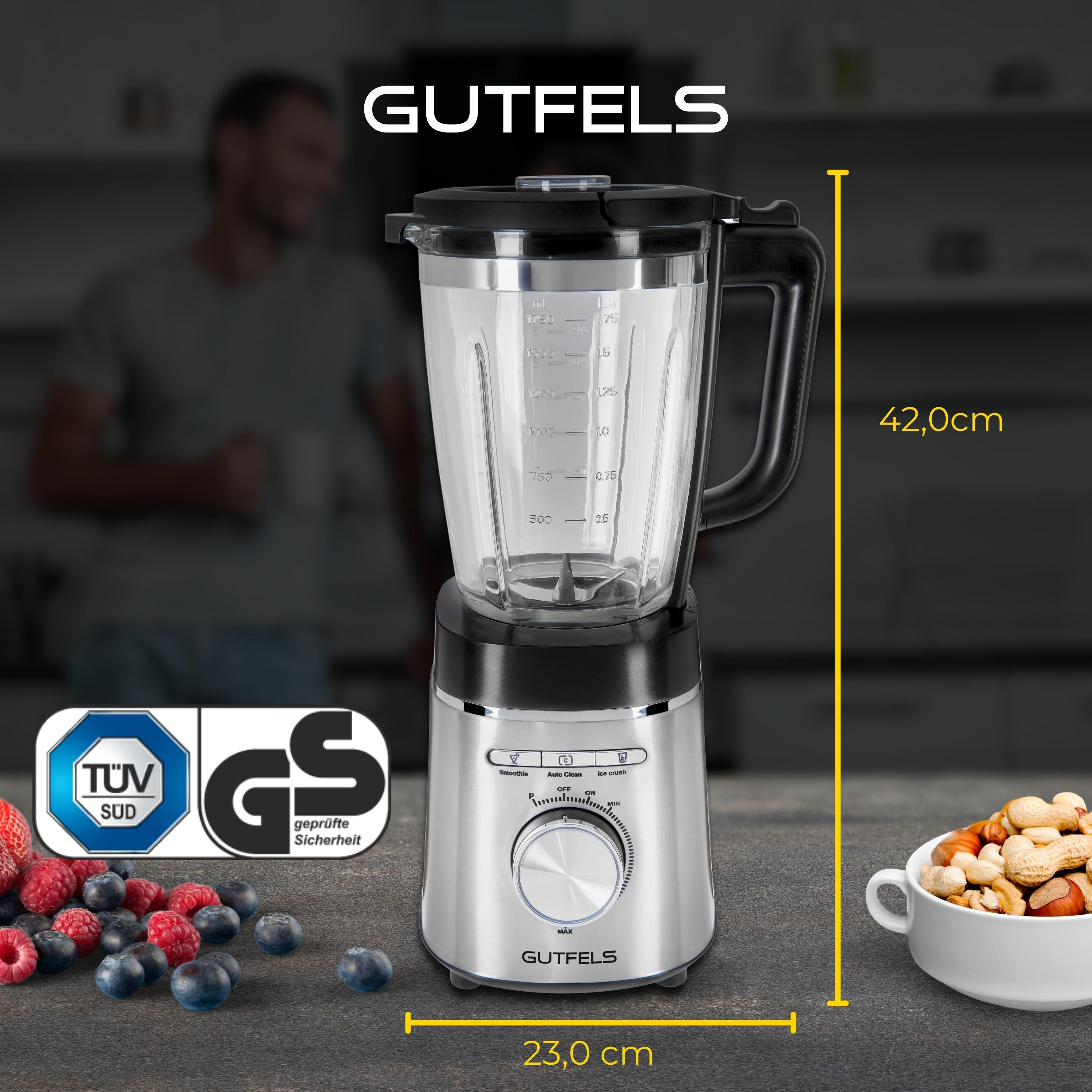 Ein silberner und schwarzer Mixer mit einem durchsichtigen Glas, Beeren und Nüssen. Der Mixer hat ein Rad.