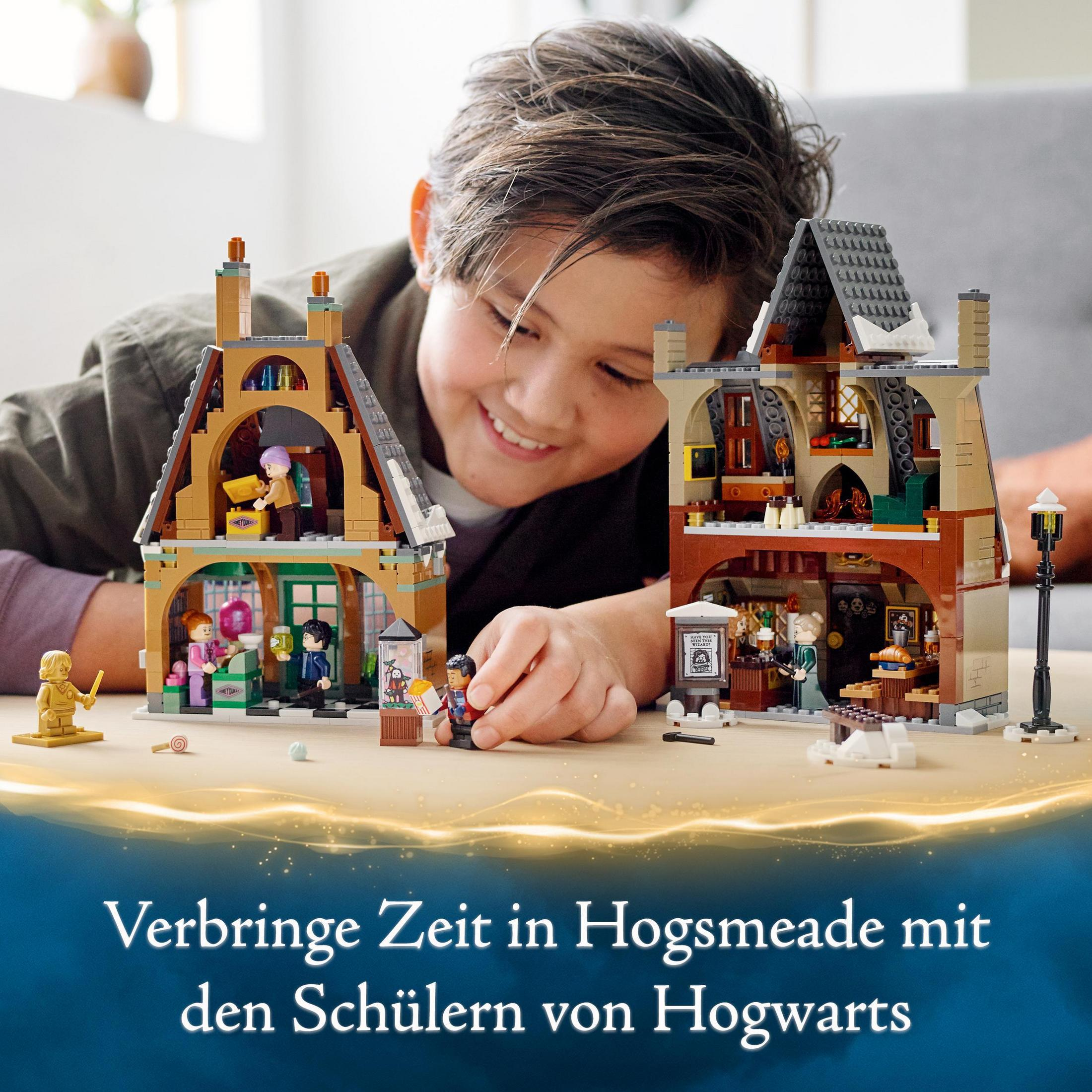 Ein Junge spielt mit einem Lego Hogwarts-Set. Zwei Lego-Gebäude stehen auf einem Tisch mit den Set-Teilen.