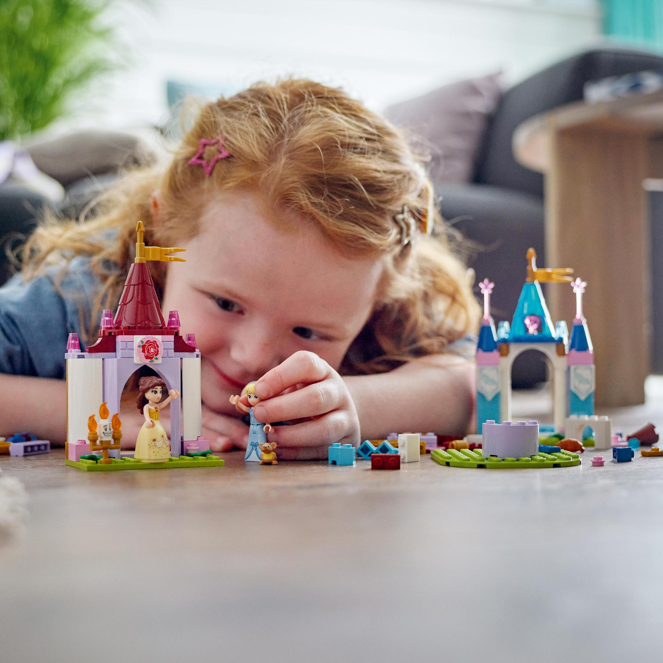 Ein Mädchen spielt mit LEGO-Burgspielzeugen, mit einer Burg, Figuren und bunten Blöcken.