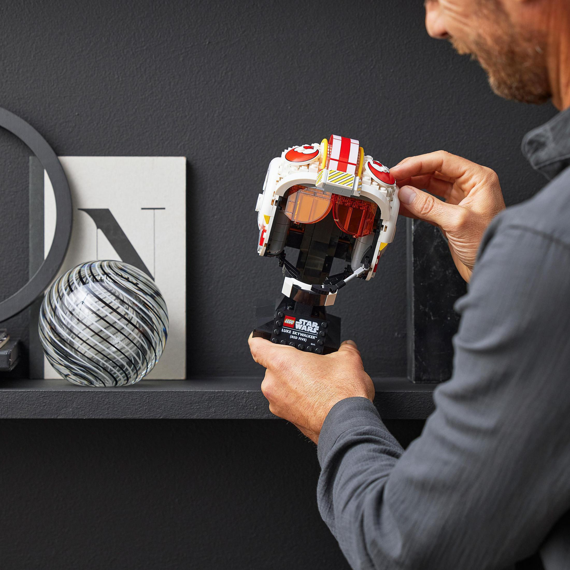 Osoba składająca hełm Lego Star Wars na czarnej powierzchni z białym i czarnym tłem.