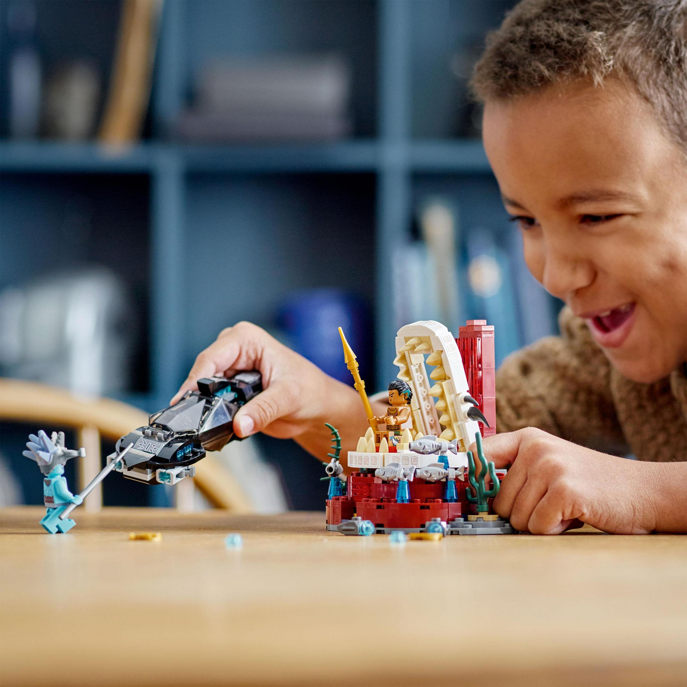 Un bambino che gioca con un set Lego, con strutture colorate e minifigure.