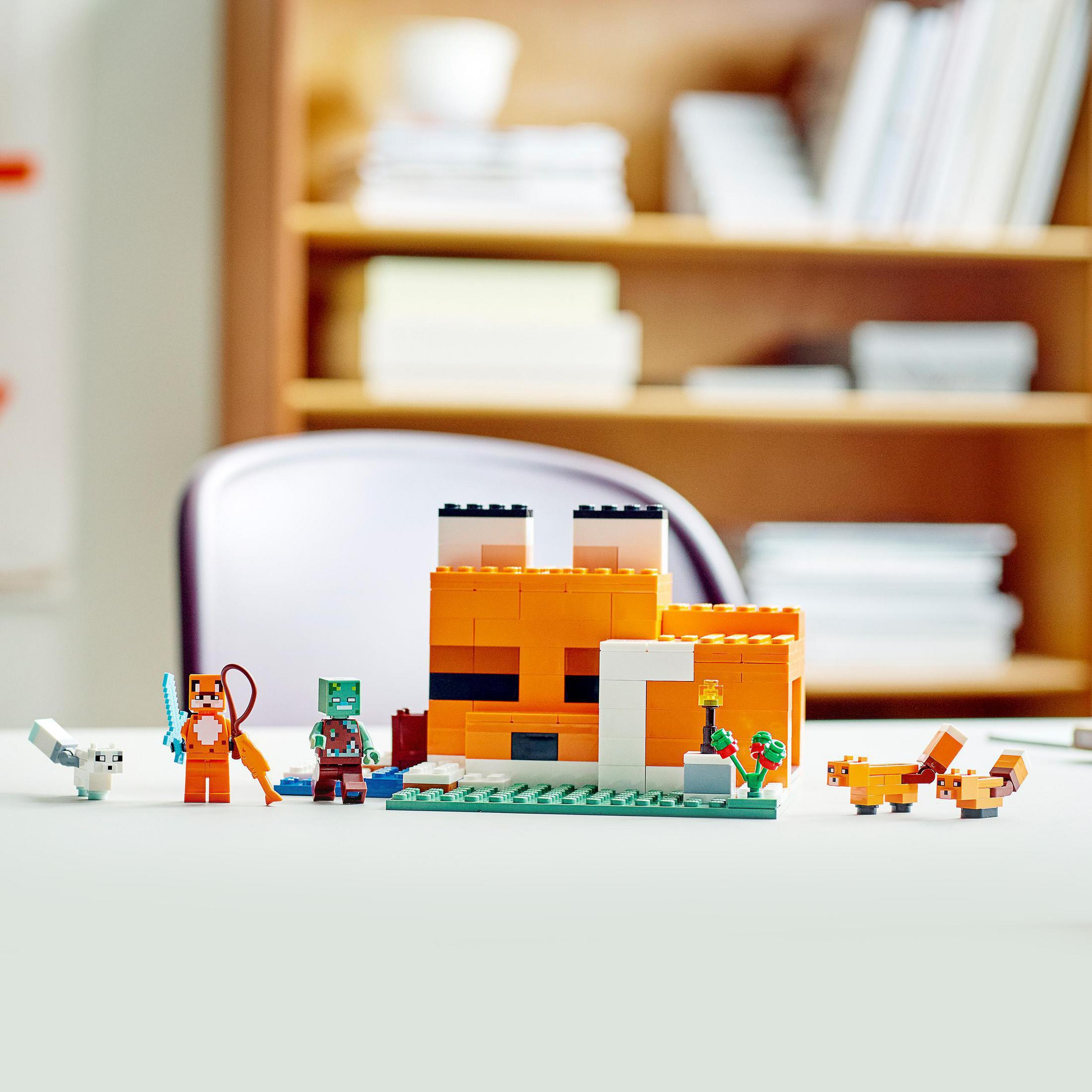 Set de Lego de una casa de zorro de Minecraft con figuras en mesa blanca, fondo de estantería.