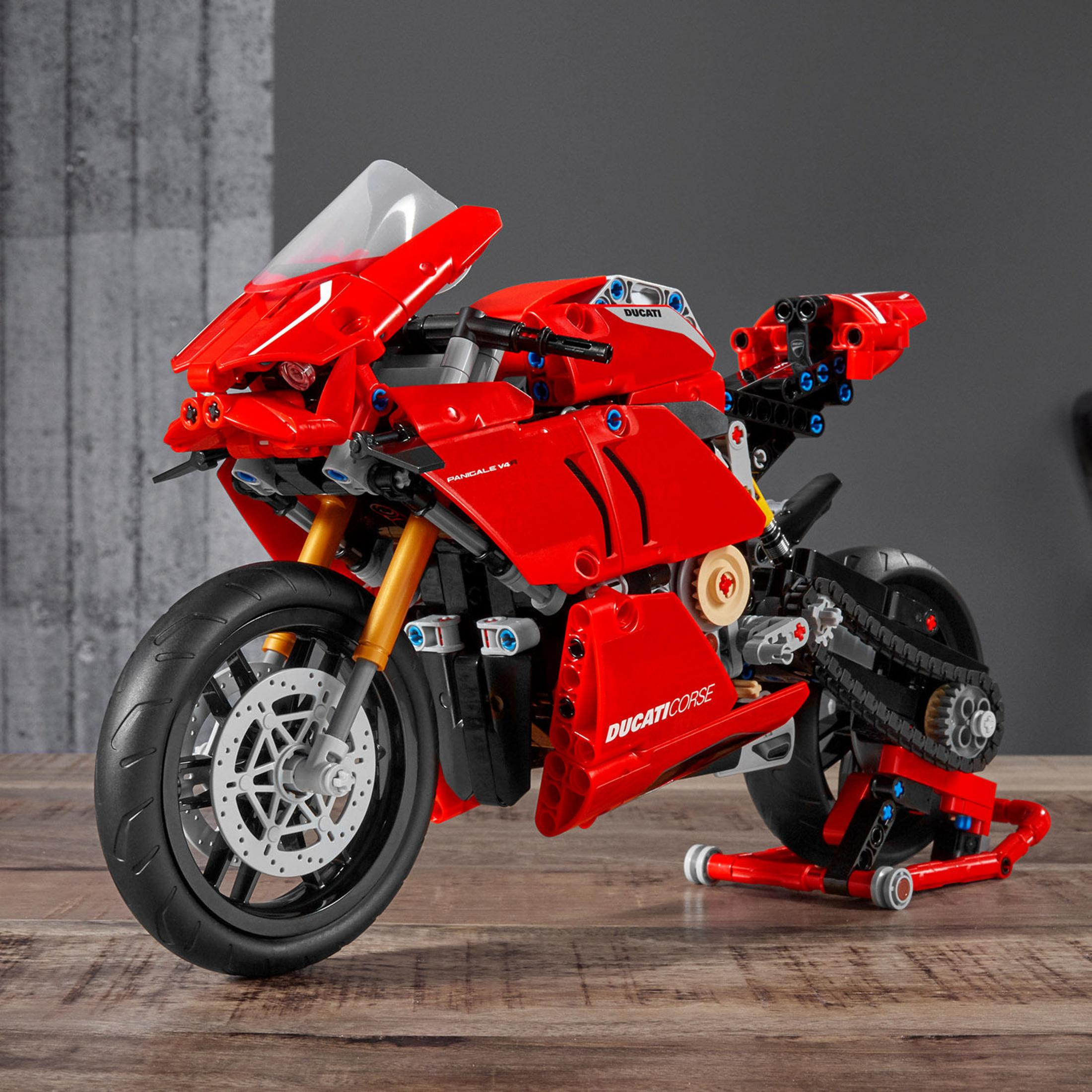 Czerwony model motocykla LEGO Ducati Panigale V4. Ma czarne koła i stoi na drewnie.