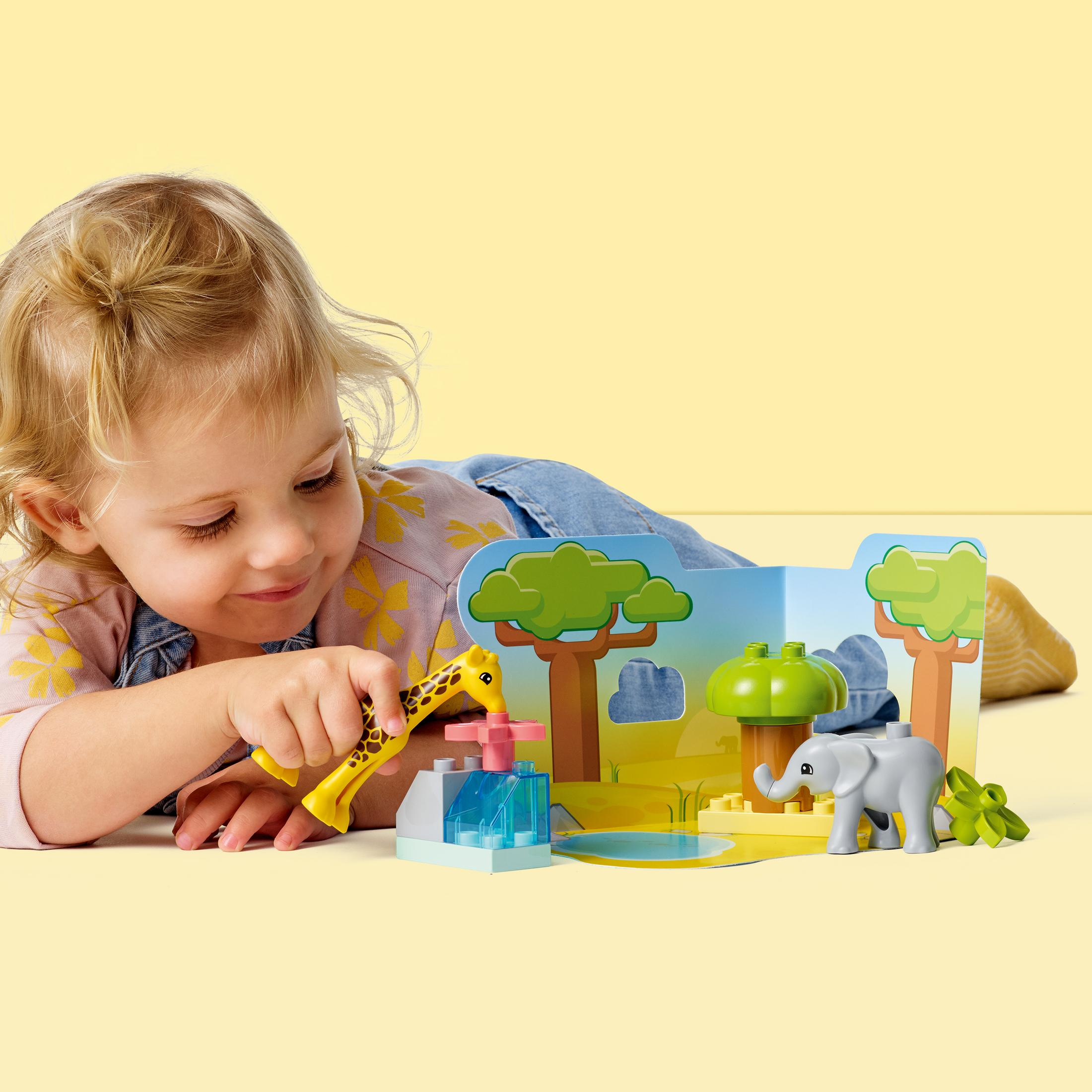 Ein Kind spielt mit einem Lego Duplo Savannen-Set, einschließlich Giraffe und Elefant.
