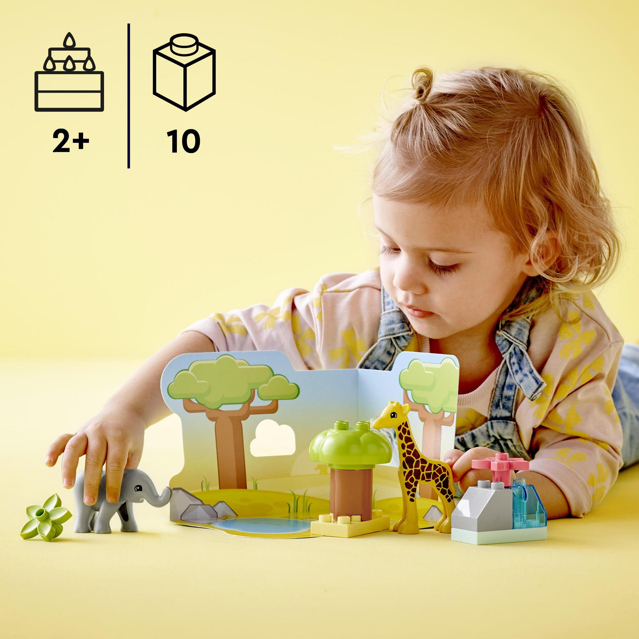 Ein Kind spielt mit einem Lego Duplo-Set einer Safari-Szene mit Tieren.