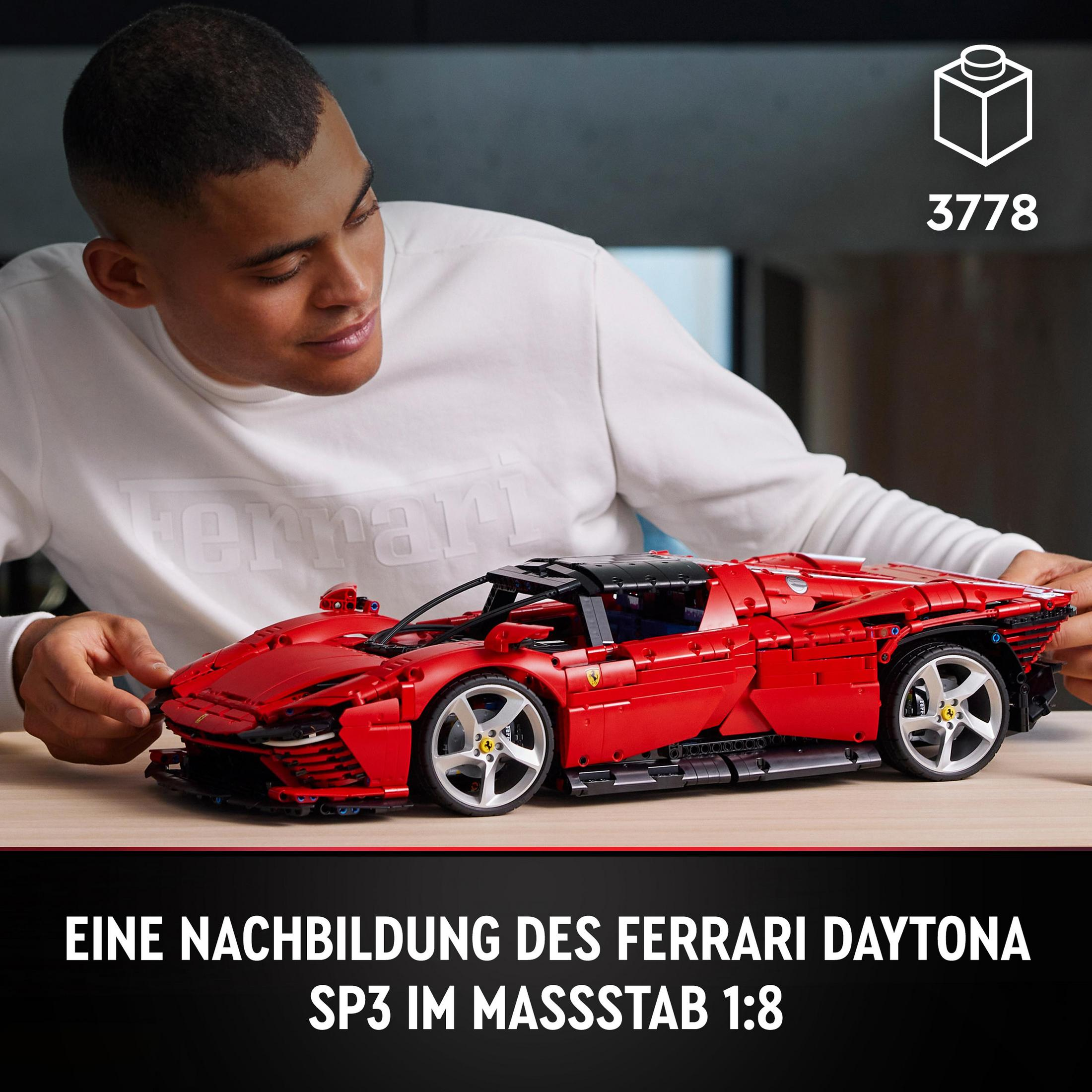 Mężczyzna buduje model czerwonego samochodu Ferrari z klocków LEGO na drewnianym stole.