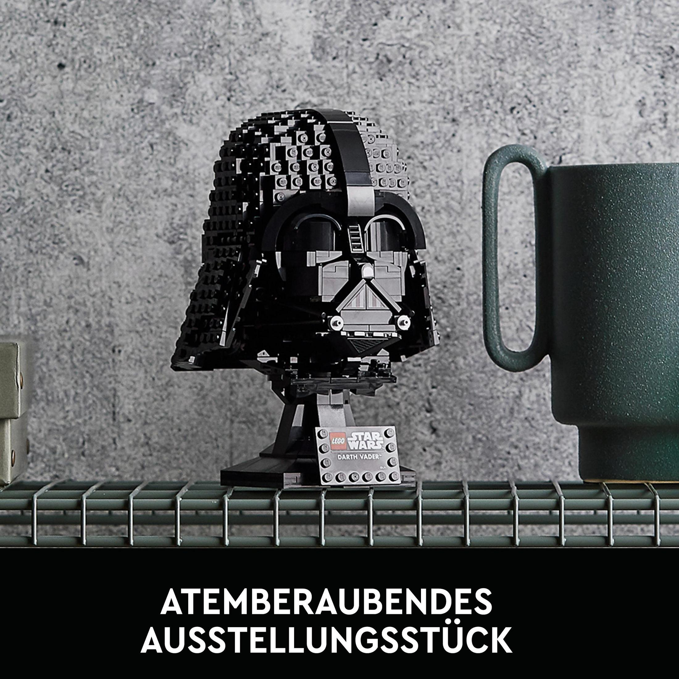 Model hełmu Lego Darth Vader na półce, obok zielony kubek.