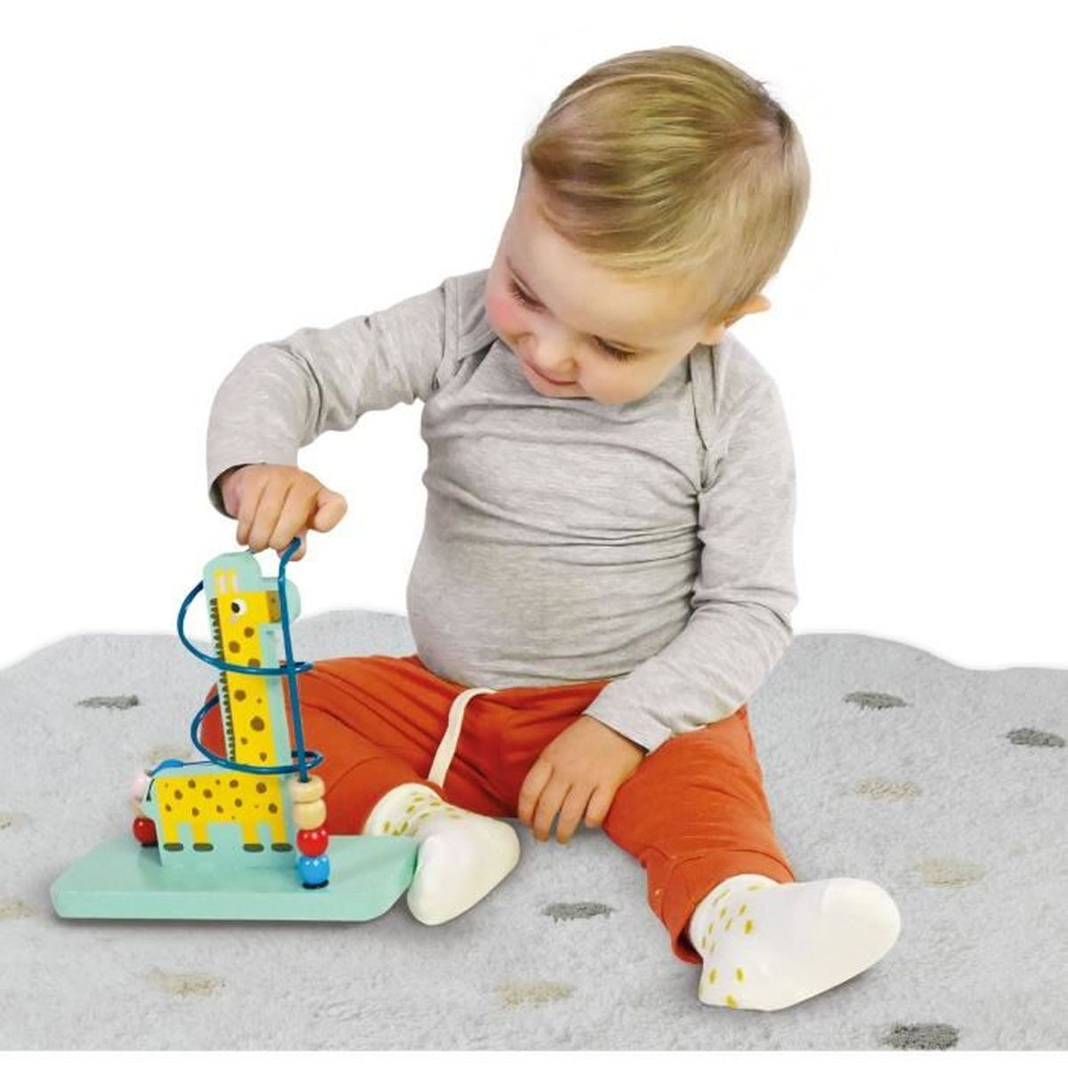 Kleinkind spielt mit einem perlenlabyrinth-Spielzeug mit Giraffenmotiven auf einer grauen Matte.