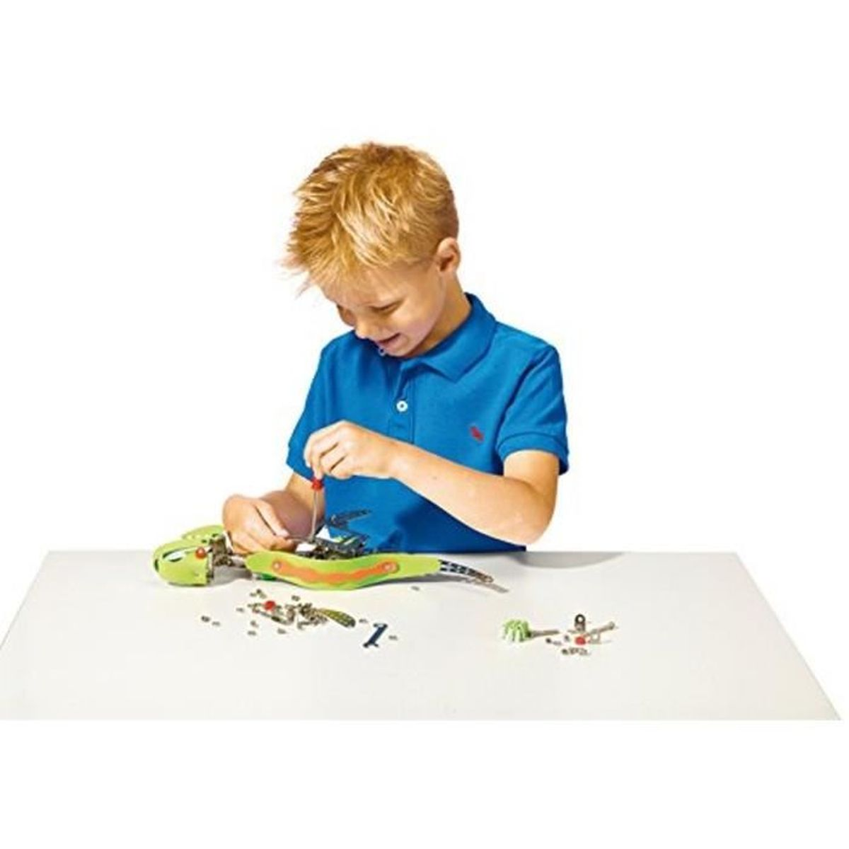 Chłopiec w niebieskiej koszuli składa zabawkę węża śrubokrętem, białe tło.