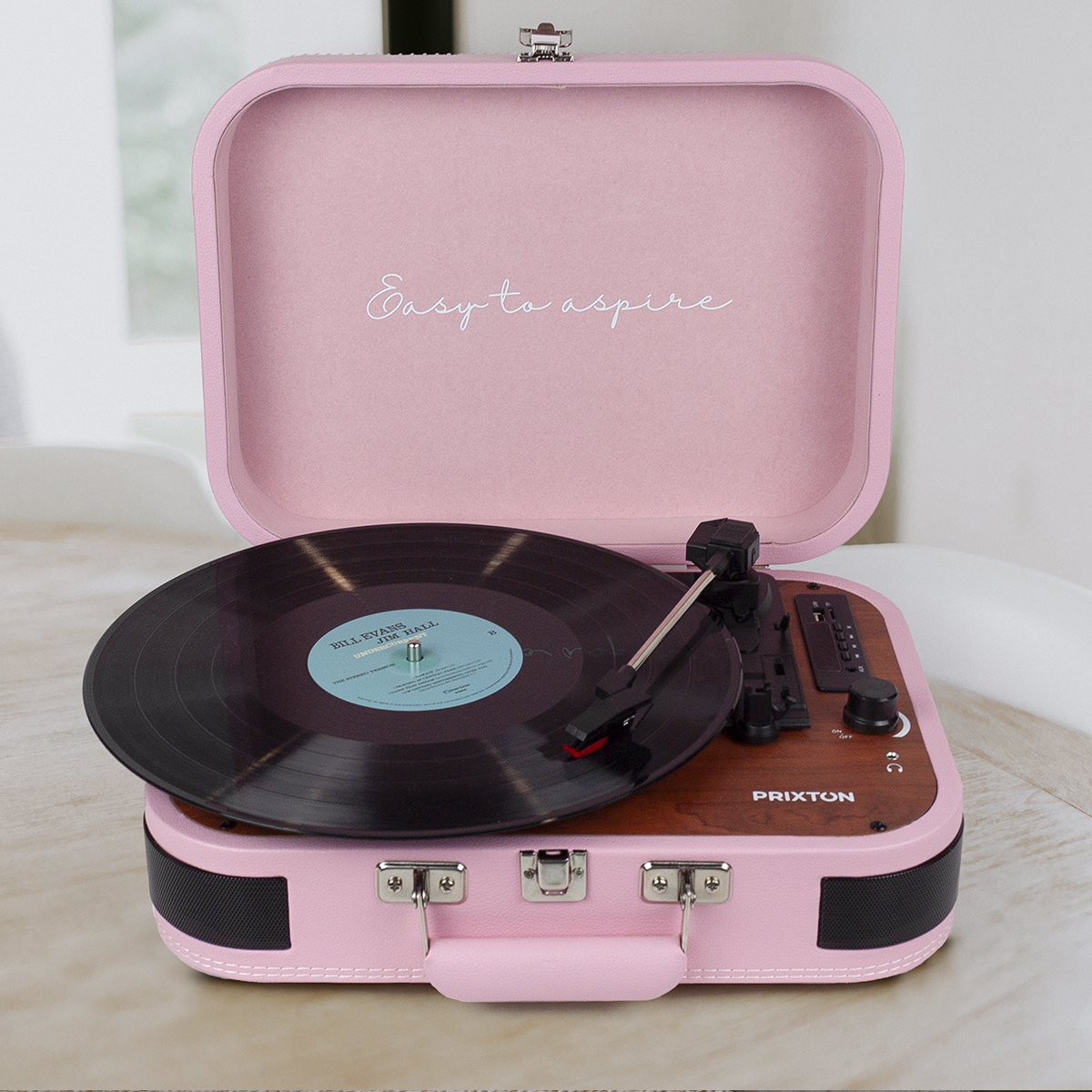 Różowy gramofon z płytą w środku, pokrywa otwarta, biały tekst na pokrywie.