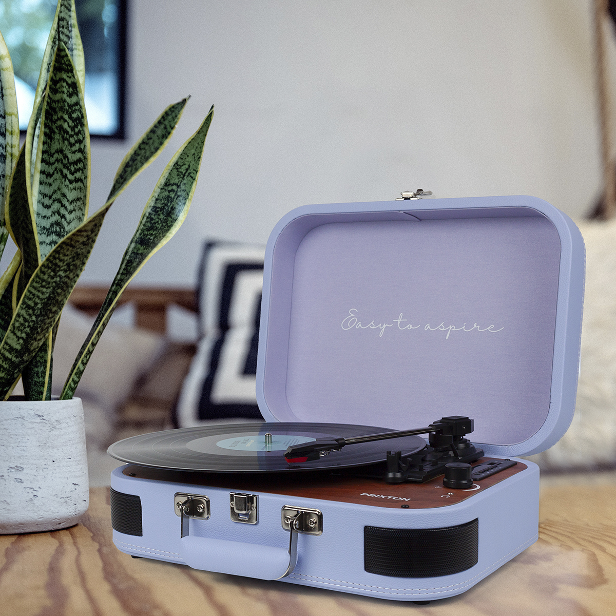 Niebieski gramofon w stylu vintage z płytą. Zielona roślina po lewej stronie.