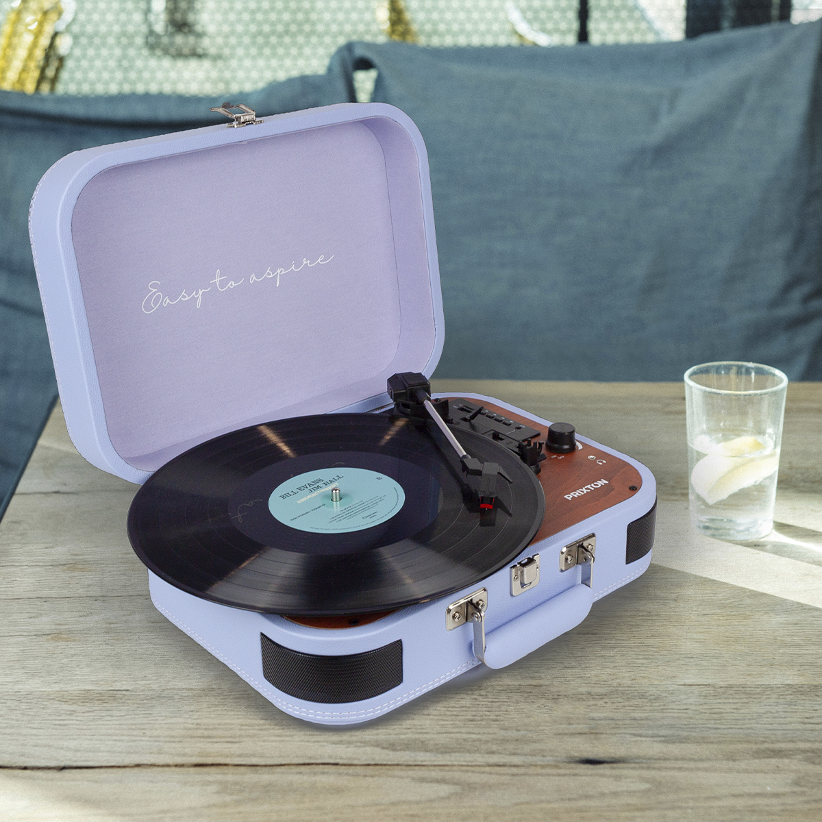 Gramofon w stylu retro z płytą winylową na drewnianym stole ze szklanką wody.