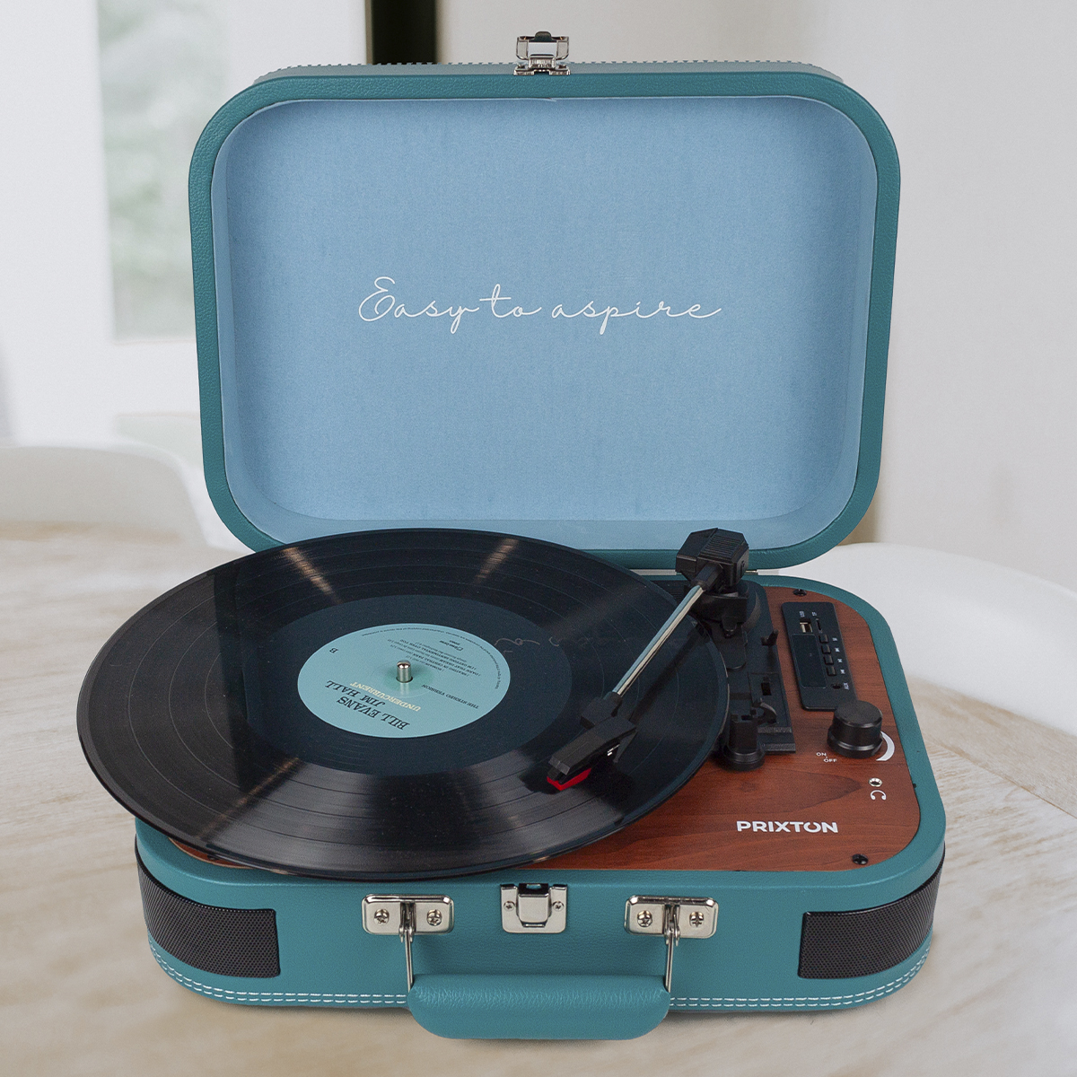 Turkusowy gramofon jest otwarty, z płytą na nim. Tekst "Easy to aspire" jest na górze.