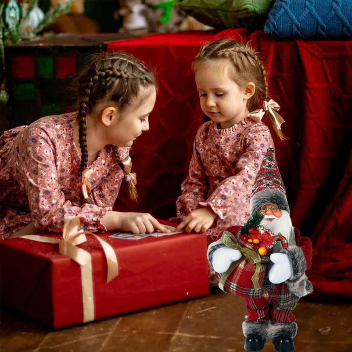 Zwei Mädchen betrachten eine rote Geschenkbox, neben ihnen eine Weihnachtsmannfigur.