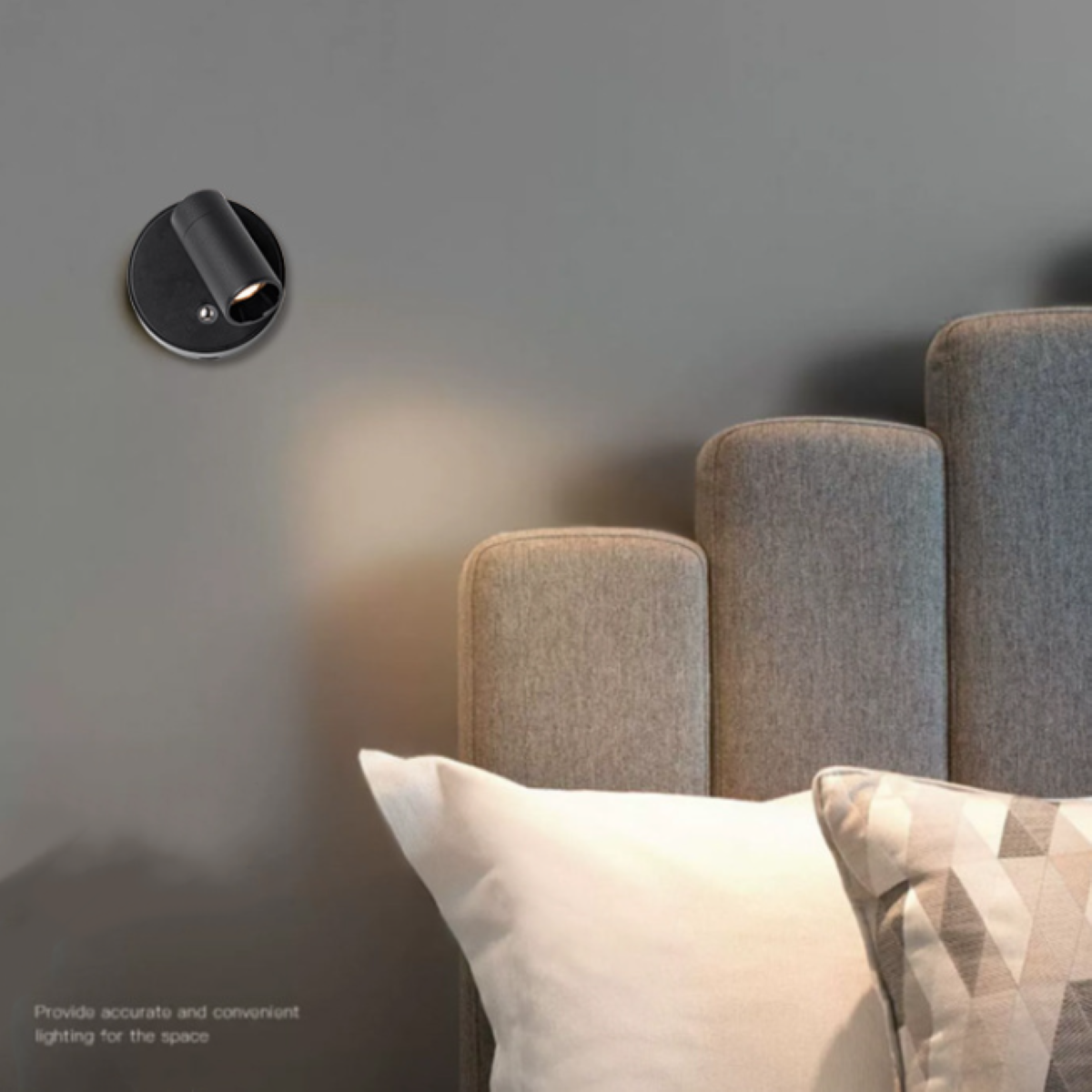 Schwarzer Wand-Spotlicht mit einem Betthaupt und Kissen im Hintergrund.