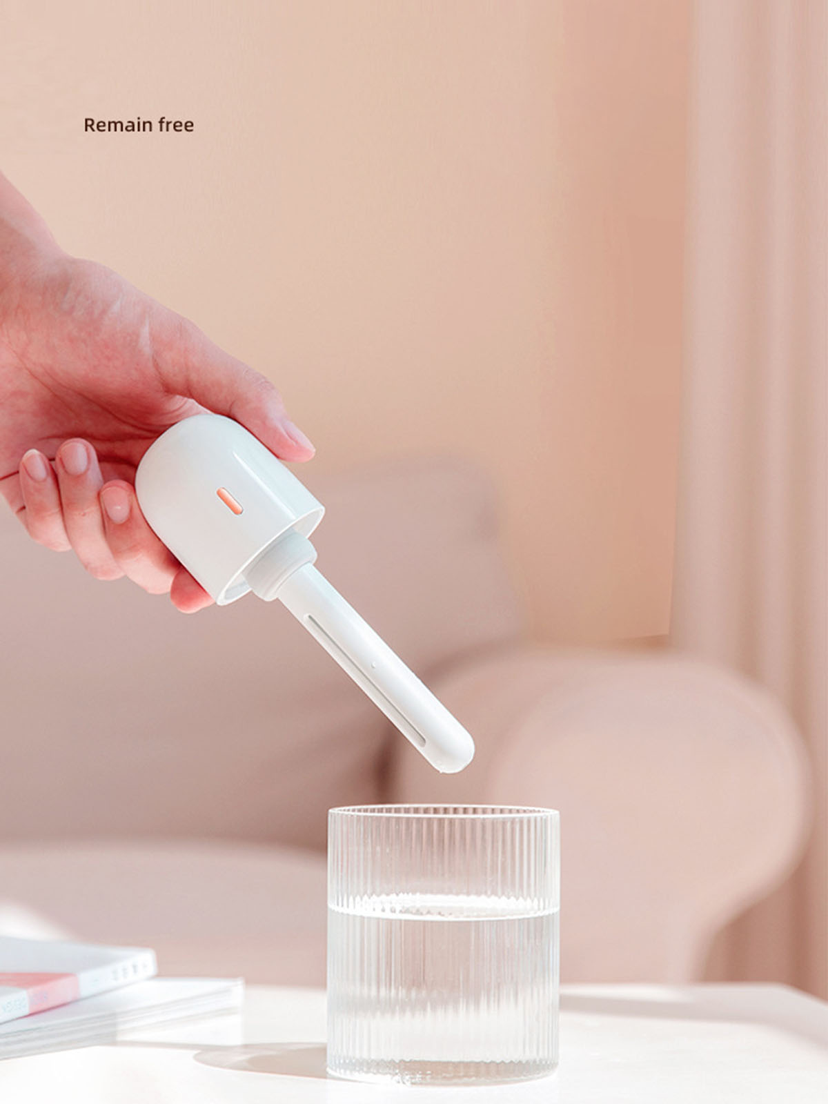Eine Hand, die einen weißen Luftbefeuchter-Zauberstab über einem Glas Wasser hält, mit den Worten „Bleib frei“.