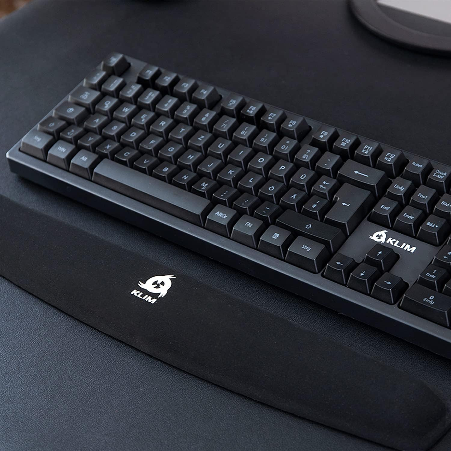 Eine schwarze Tastatur mit Handballenauflage. Die Tastatur hat englische Buchstaben und ein KLIM-Logo.