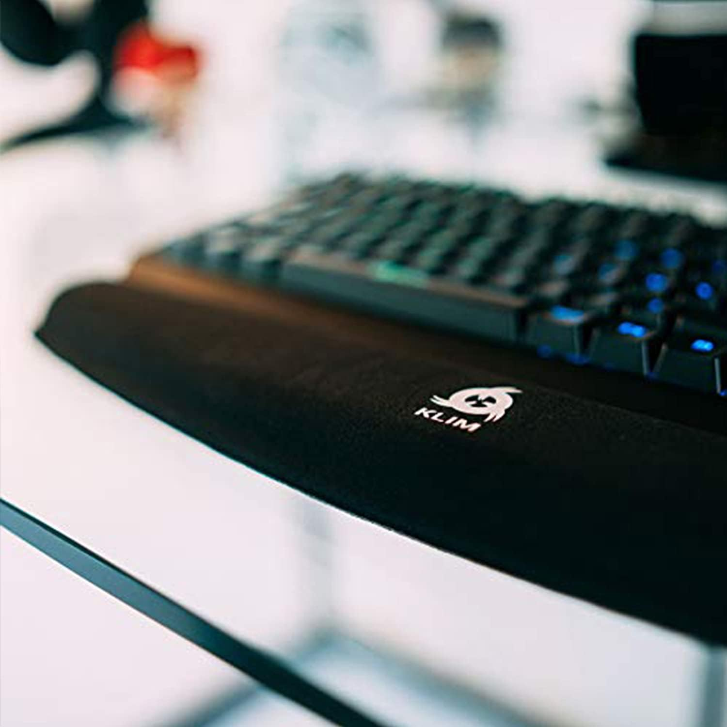 Nahaufnahme einer Tastatur mit Handballenauflage auf einem Glastisch.