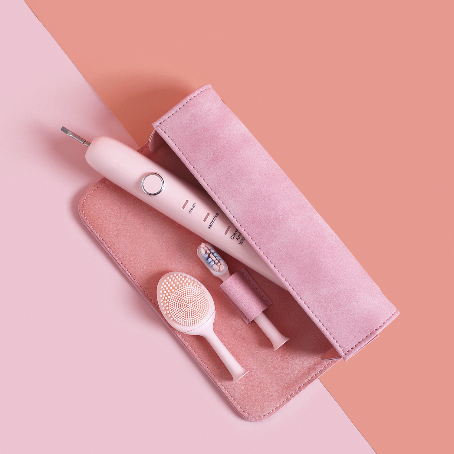 Spazzolino elettrico rosa con accessori in una custodia rosa, su sfondo rosa a due tonalità.