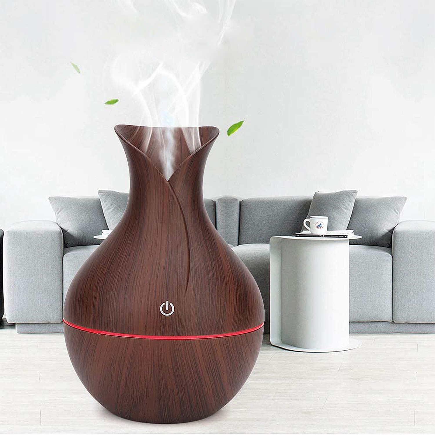 Ein brauner Holzdiffusor. Weißer Dampf kommt heraus. Dahinter ein graues Sofa. Rechts ein weißer Tisch.