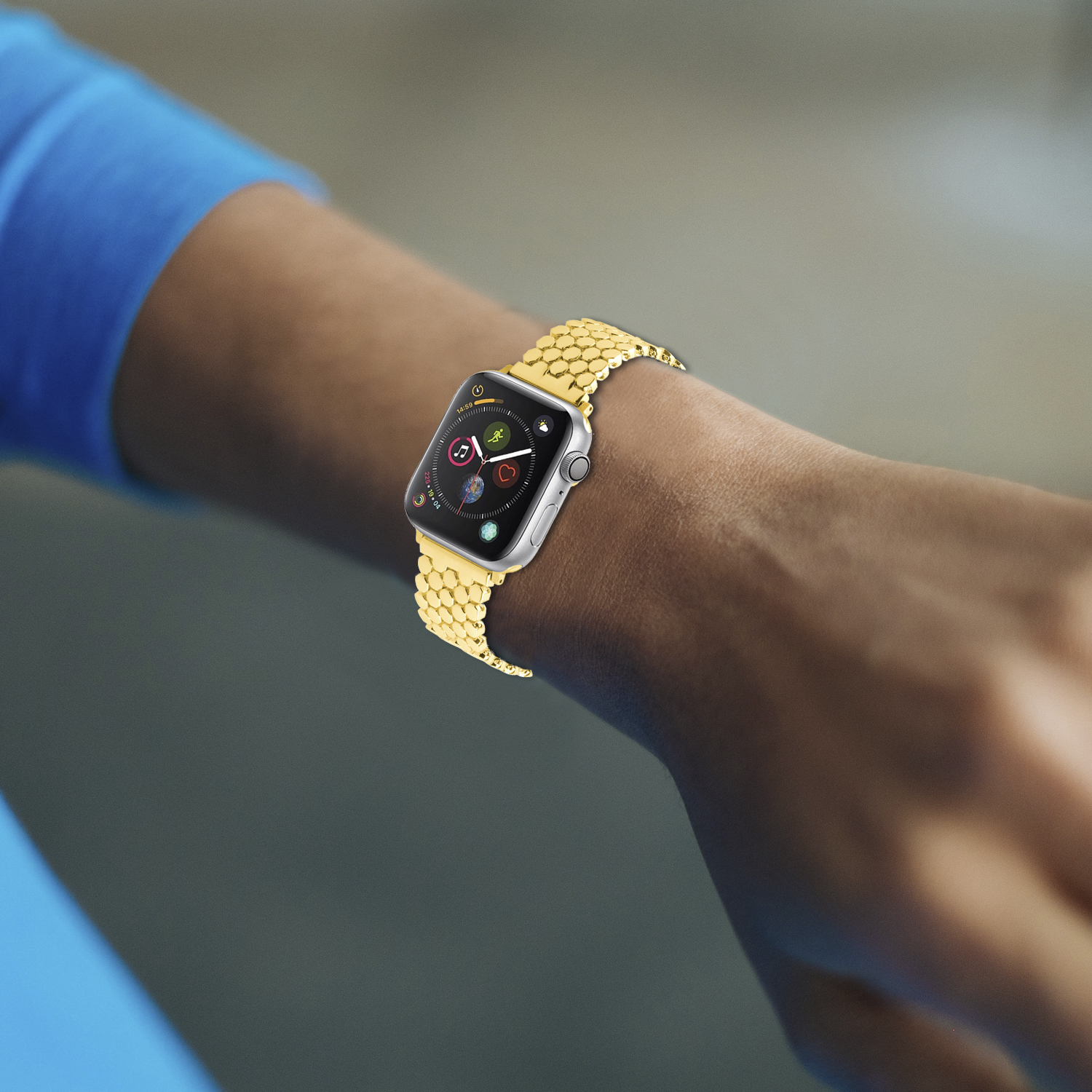 Persona usando un Apple Watch plateado con una banda dorada. El reloj muestra iconos en su pantalla.