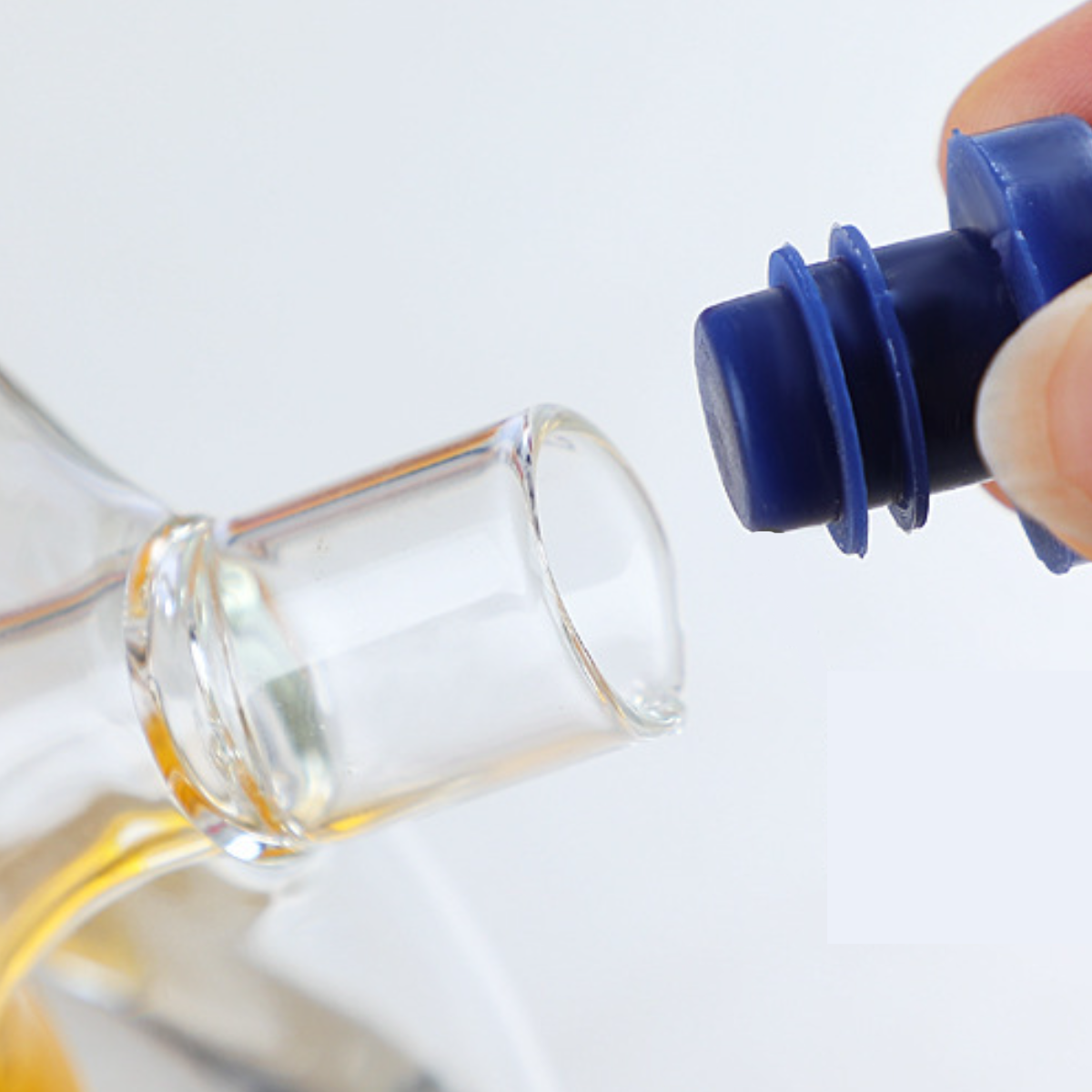 Eine Flasche mit Öl, ein blauer Verschluss wird in die Öffnung gesteckt.