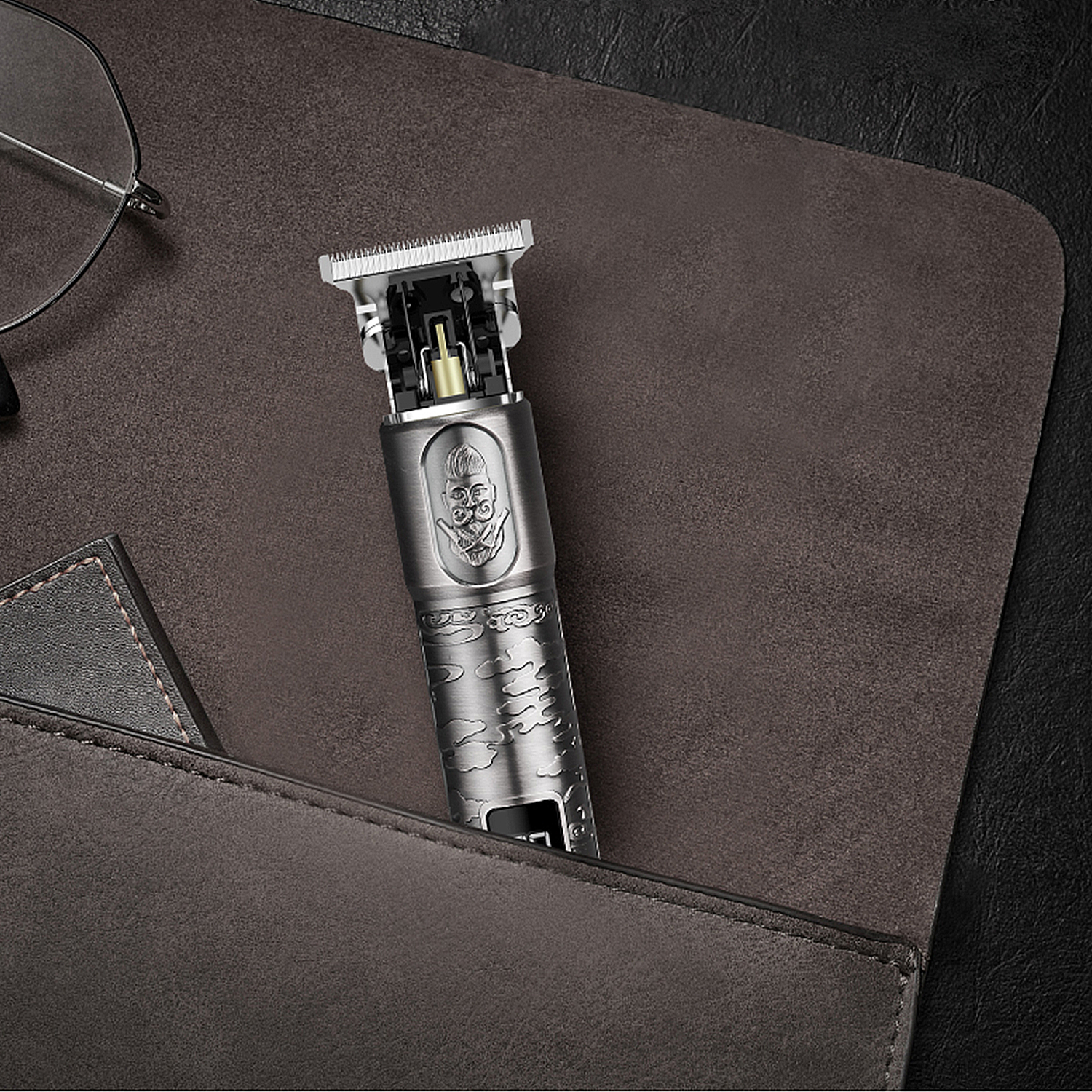 Una cortadora de cabello eléctrica plateada y negra, con un diseño de calavera, descansa en un estuche de cuero marrón.