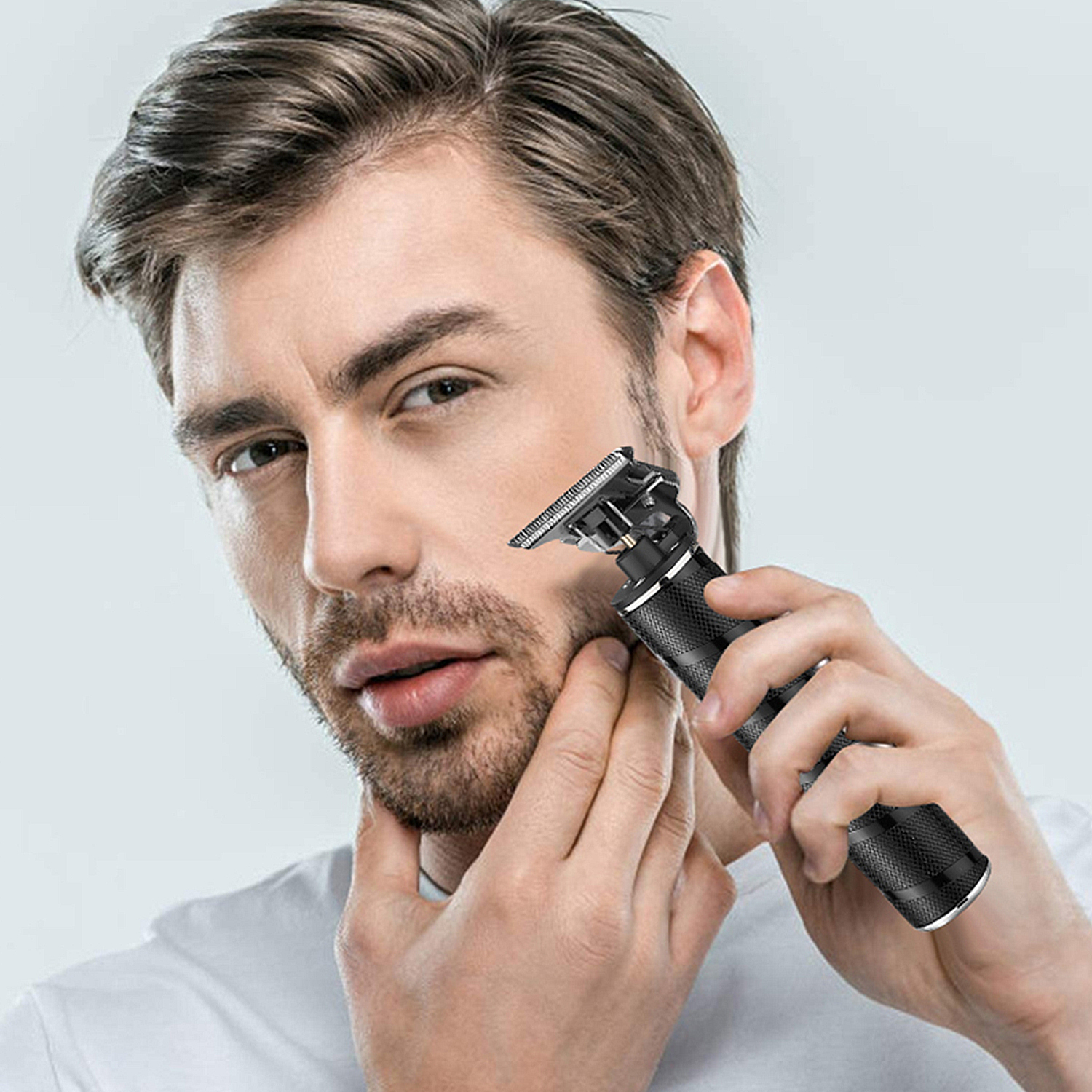 Hombre afeitándose la barba con una recortadora eléctrica. Primer plano, fondo blanco.
