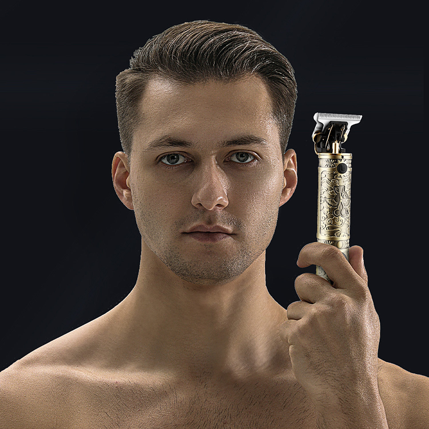 Un hombre sosteniendo una cortadora de cabello dorada. Está sin camisa con fondo negro.