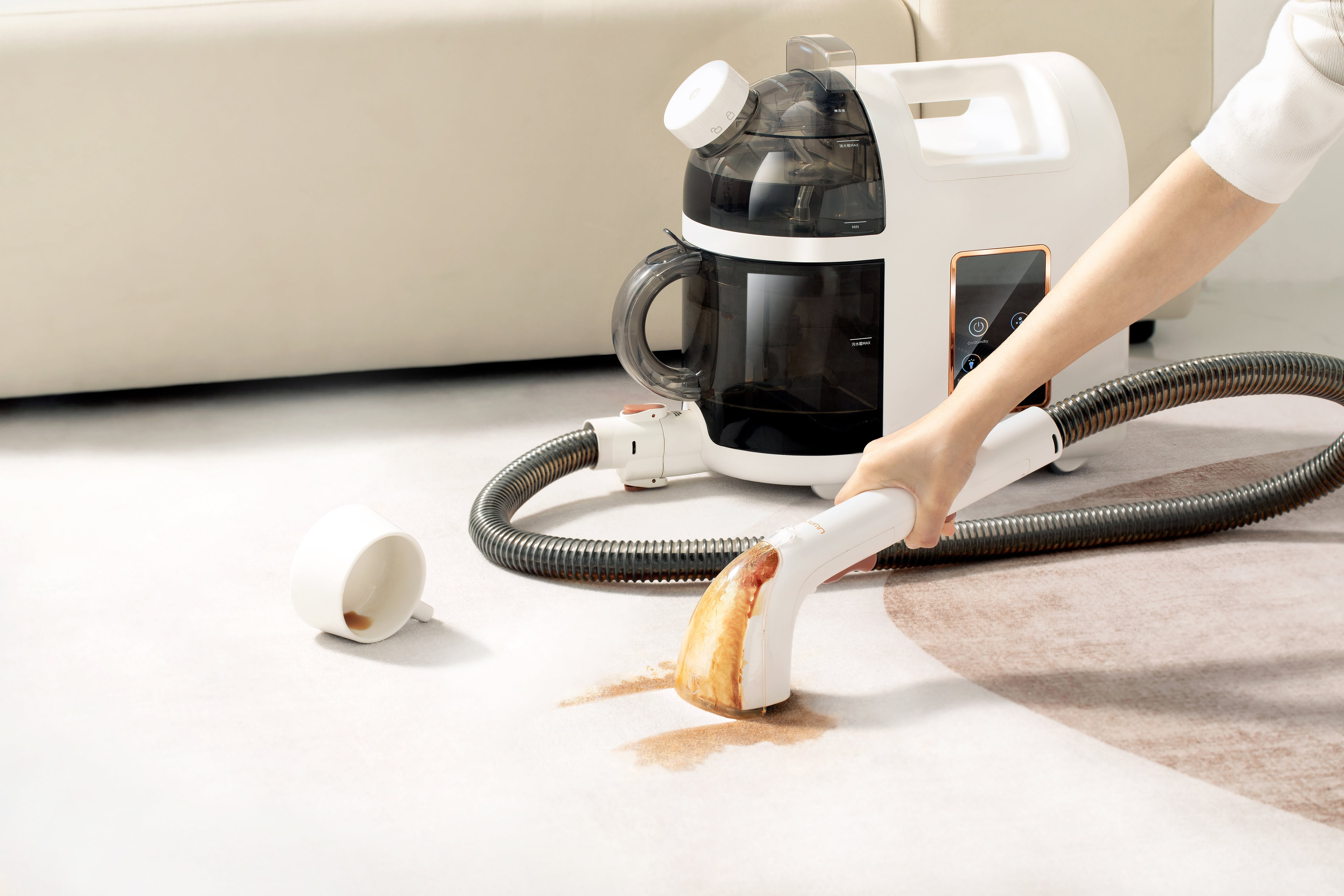 Ein weißer Teppichreiniger mit einer Hand, die einen braunen Fleck auf einem hellen Teppich reinigt.